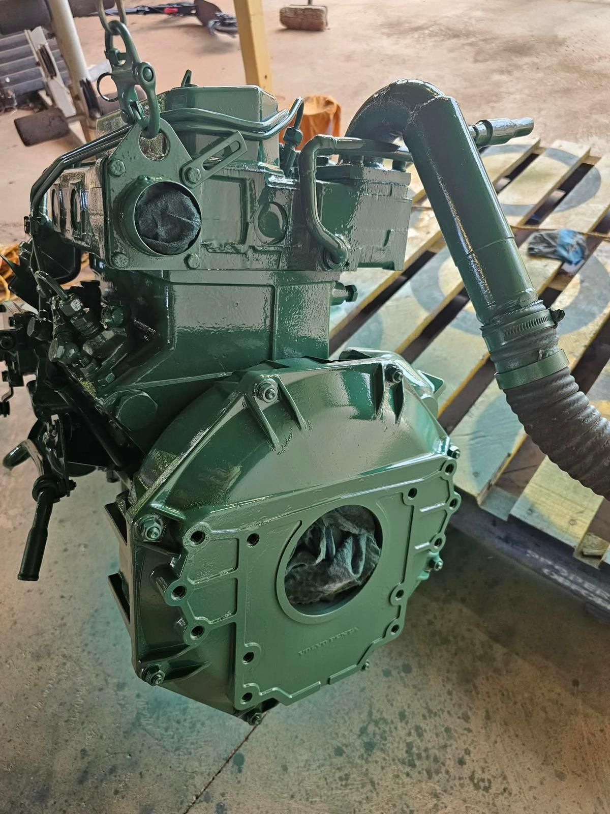 A freshly painted dark green industrial engine sits on a wooden pallet in a workshop, viewed from the rear. — Ocean Mate Marine Services in Coomera, QLD