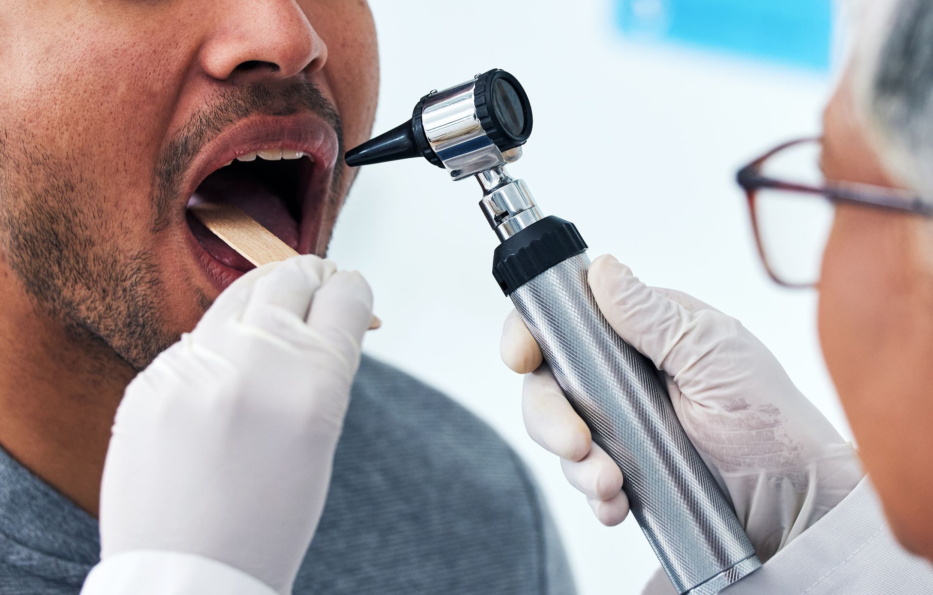 A man is having his throat examined by a doctor.