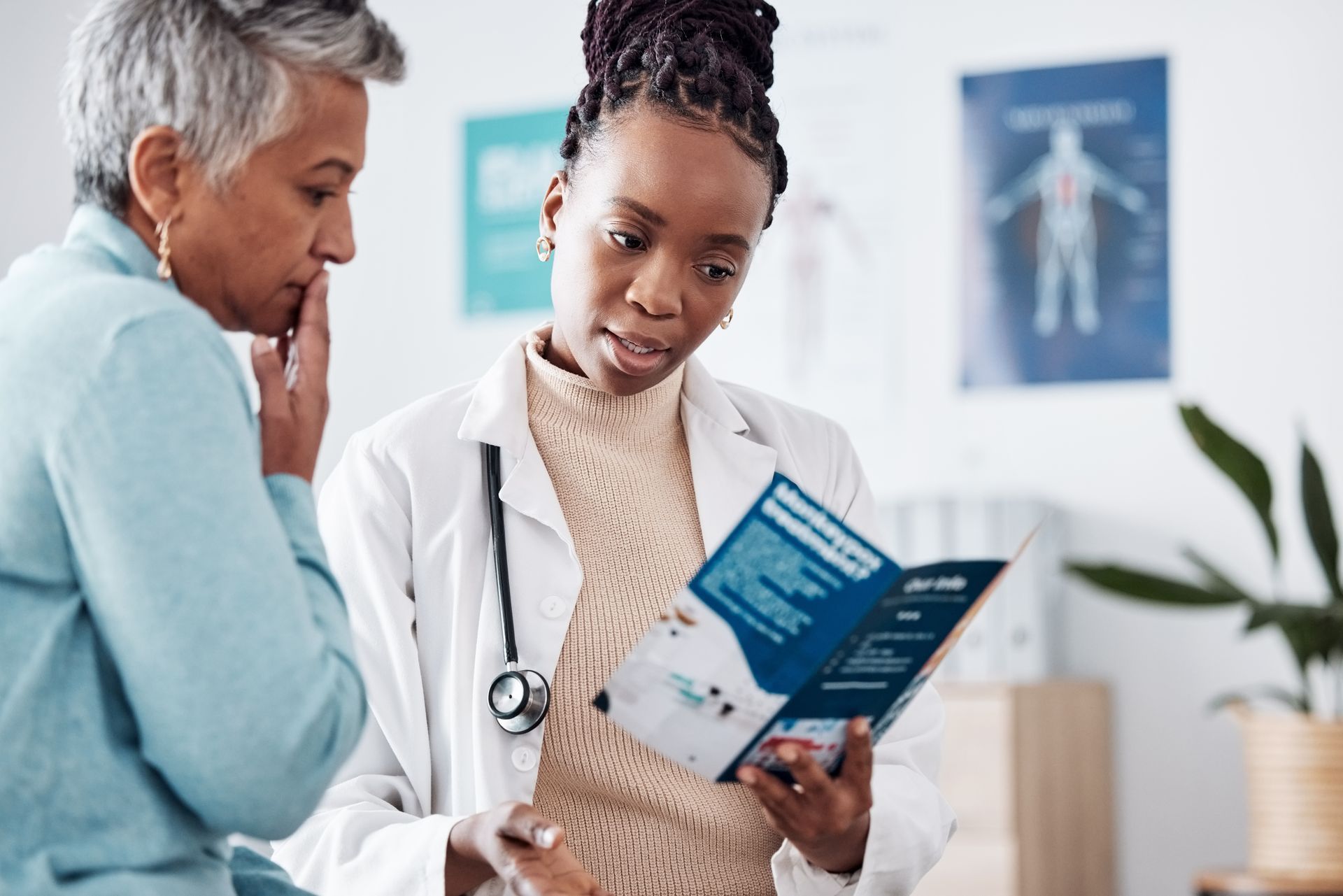 A doctor is talking to an older woman while holding a brochure.