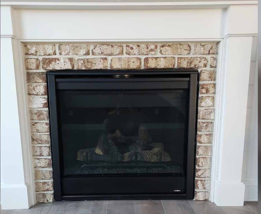 a fireplace with a brick mantle and a black screen .