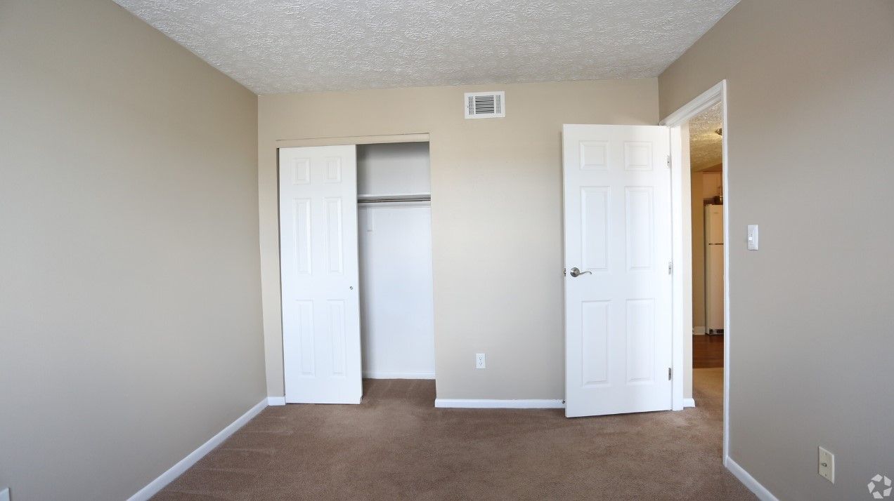 An empty bedroom with a closet and two doors