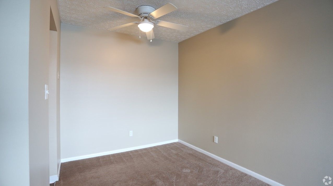 An empty bedroom with a ceiling fan and a light.
