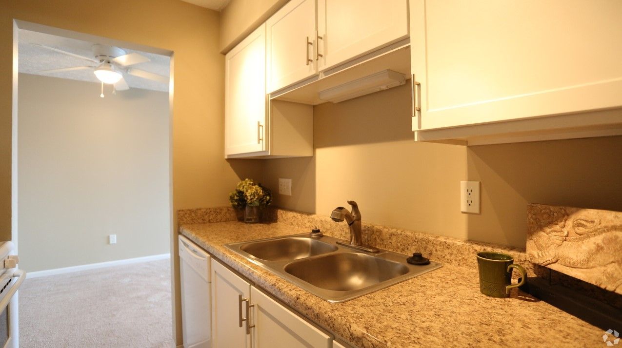 A kitchen with a sink , cabinets and granite counter tops.