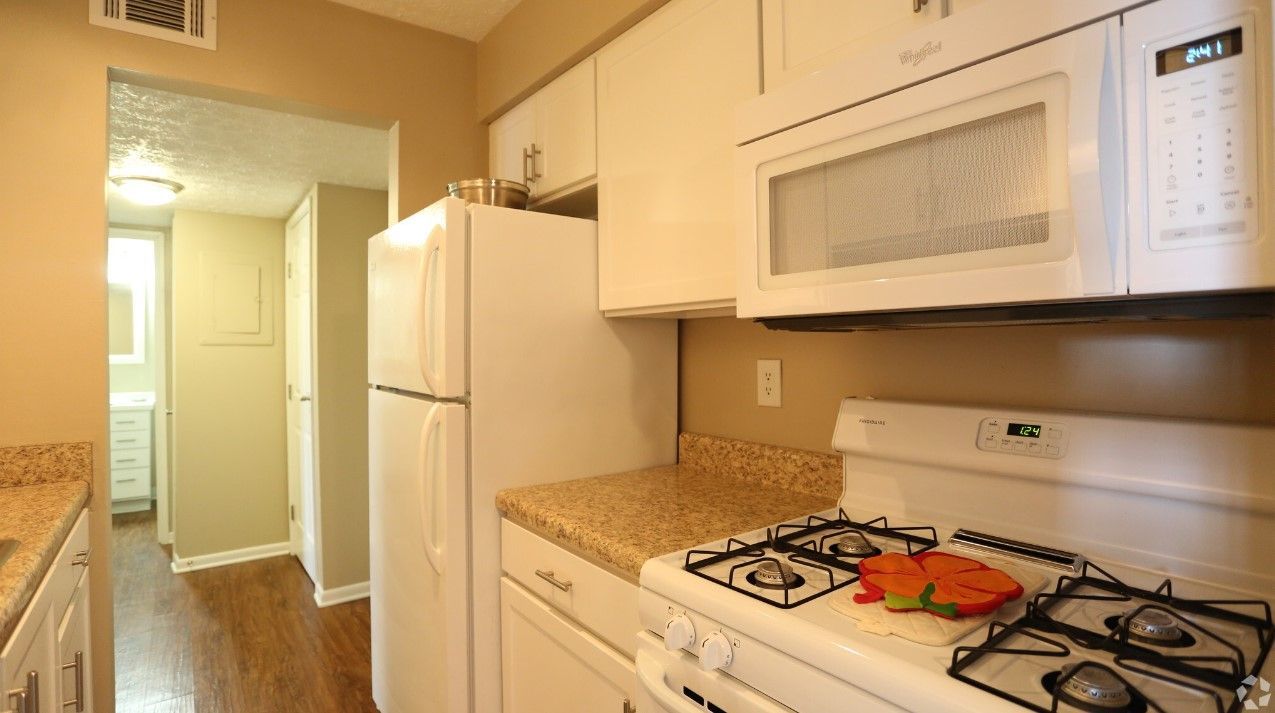 A kitchen with a stove , refrigerator , and microwave.