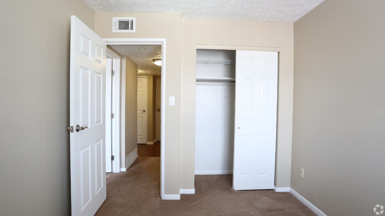 An empty bedroom with a closet and a door open
