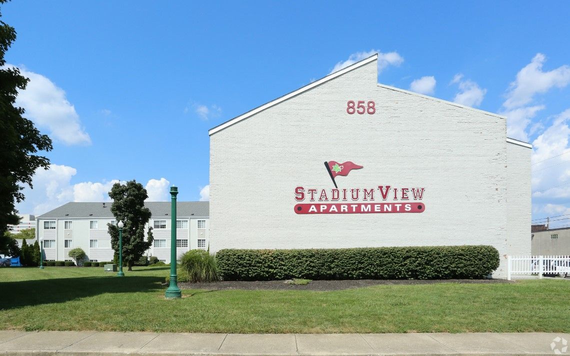 A white building with a red sign that says stadium view apartments