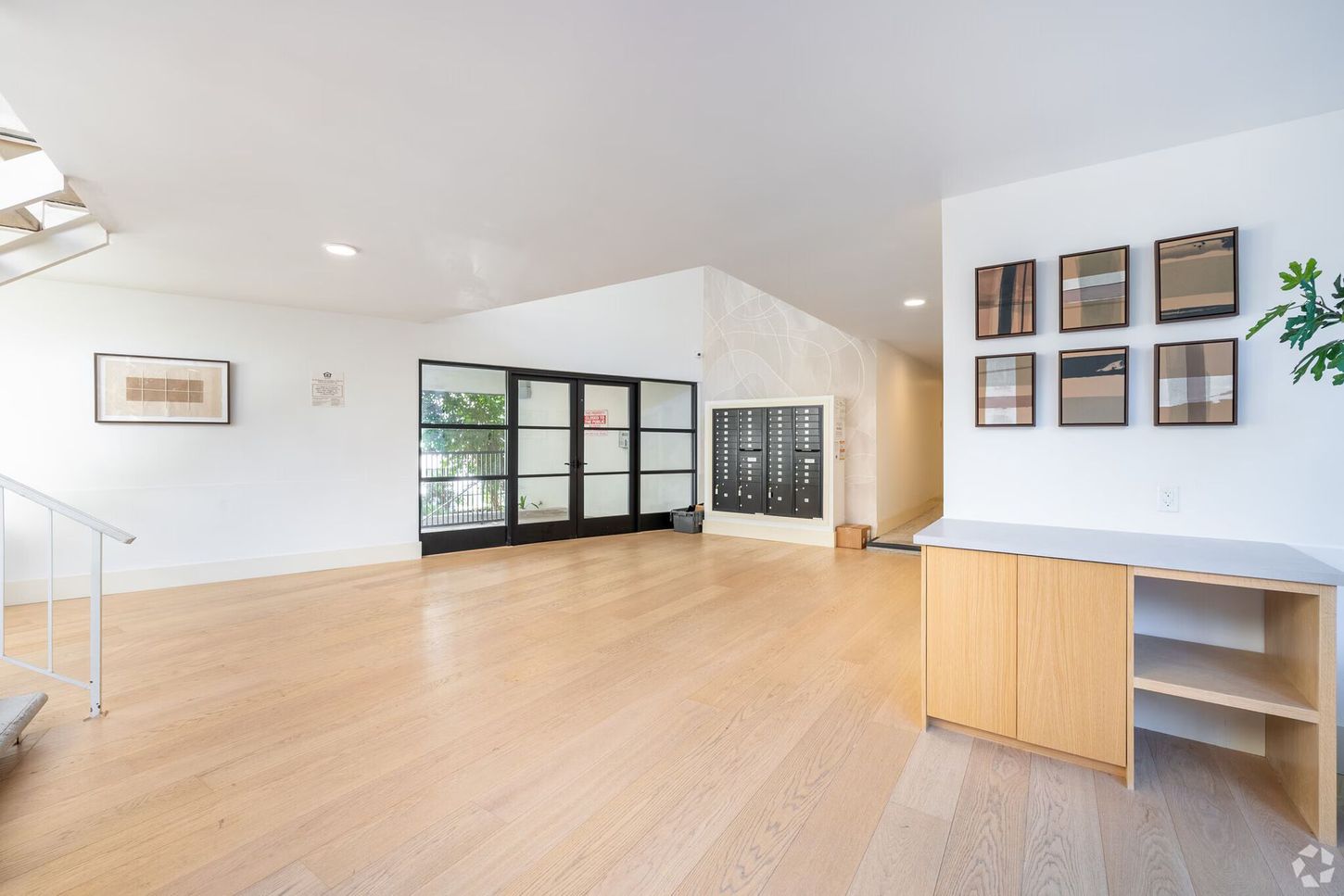 Spacious, empty room with light wood floors, white walls, and built-in shelving and cabinets.