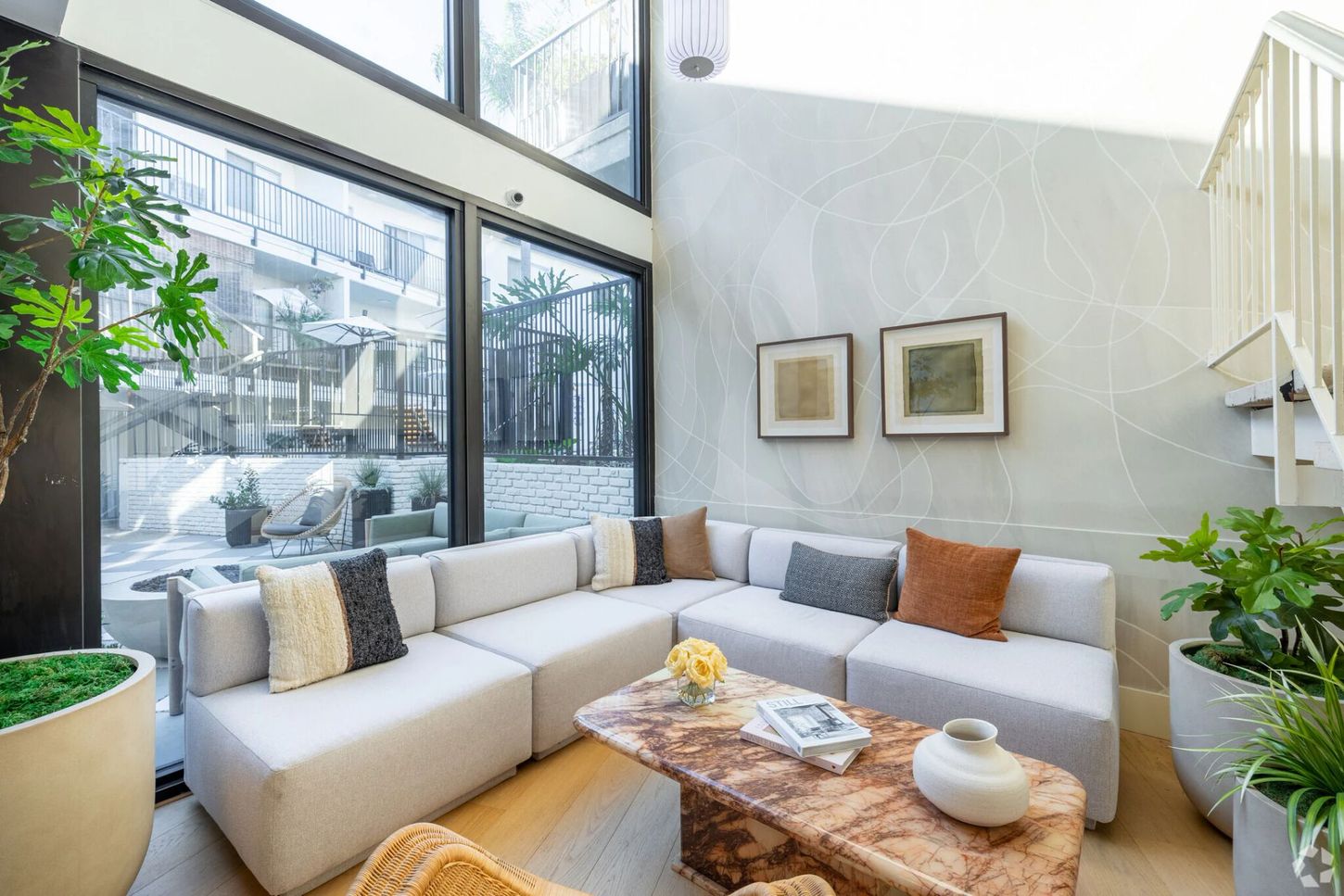 Modern living room with sectional sofa, marble coffee table, and large windows.