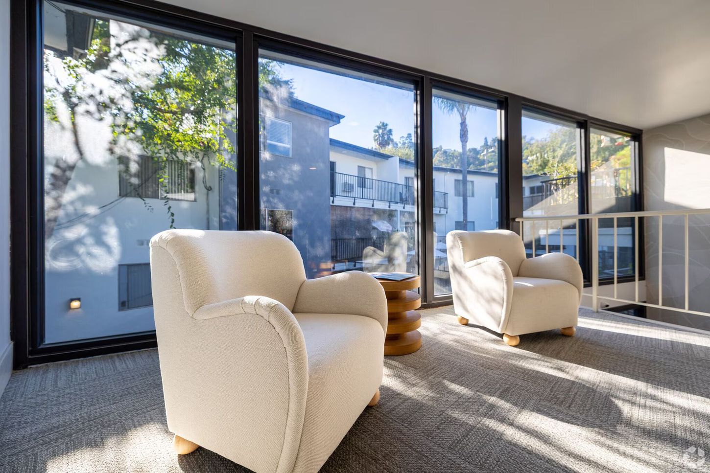 Two cream armchairs sit by large windows overlooking a courtyard.
