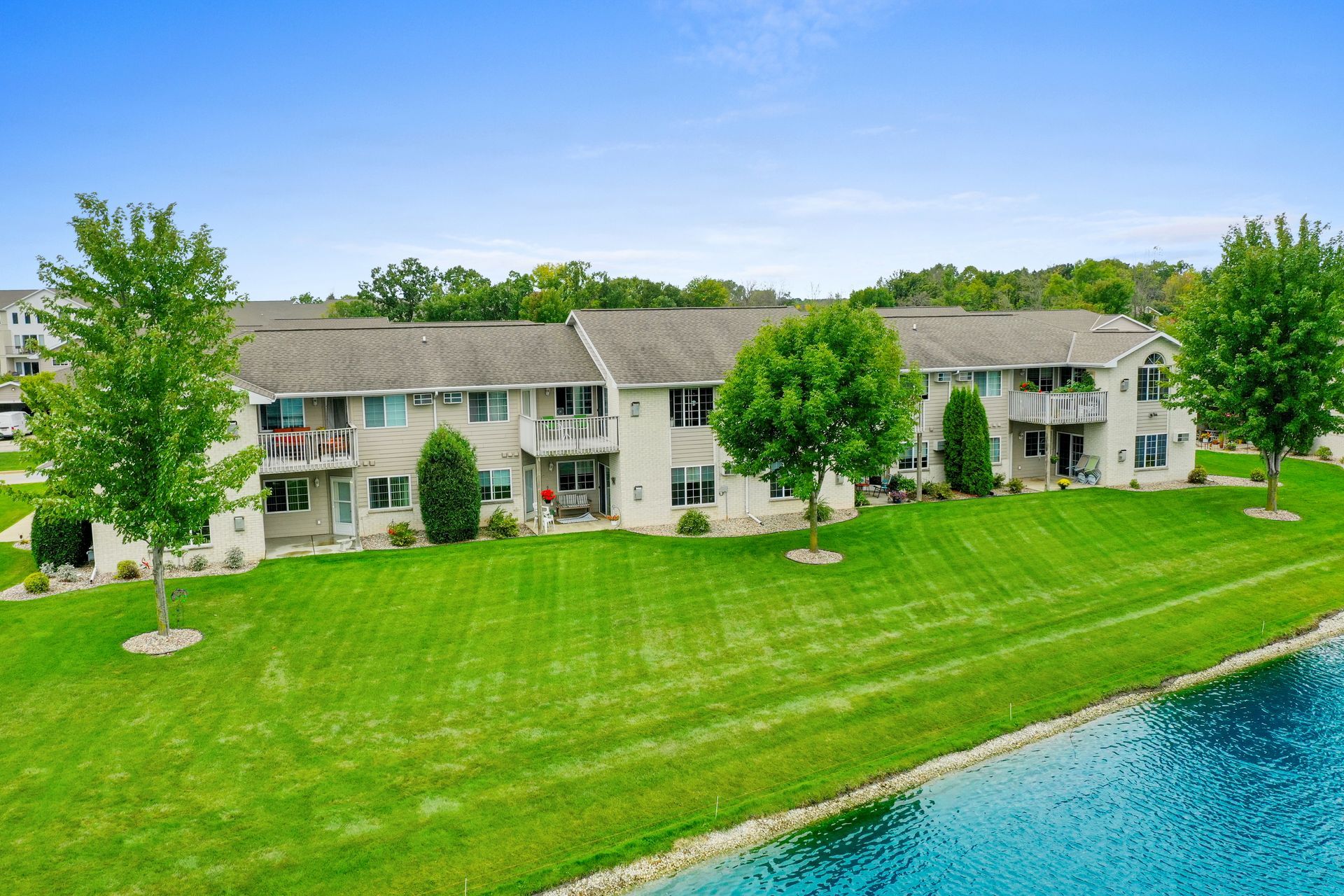 Apartment buildings beside a manicured green lawn and blue water on a sunny day