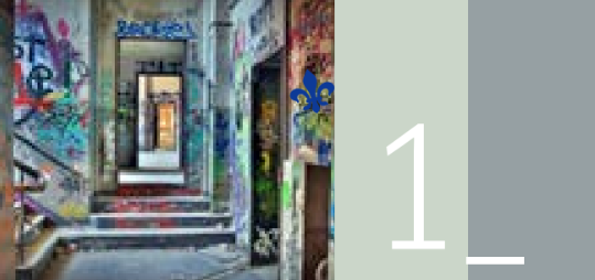 A graffiti-covered hallway with stairs leading to a doorway, next to a pale green block displaying the number 1.