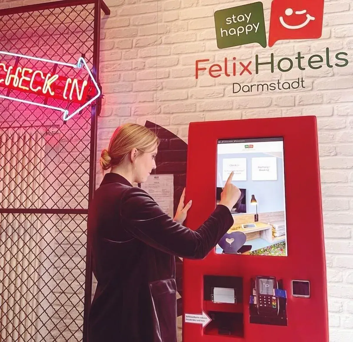 A person using a red self-service check-in terminal at FelixHotels Darmstadt.