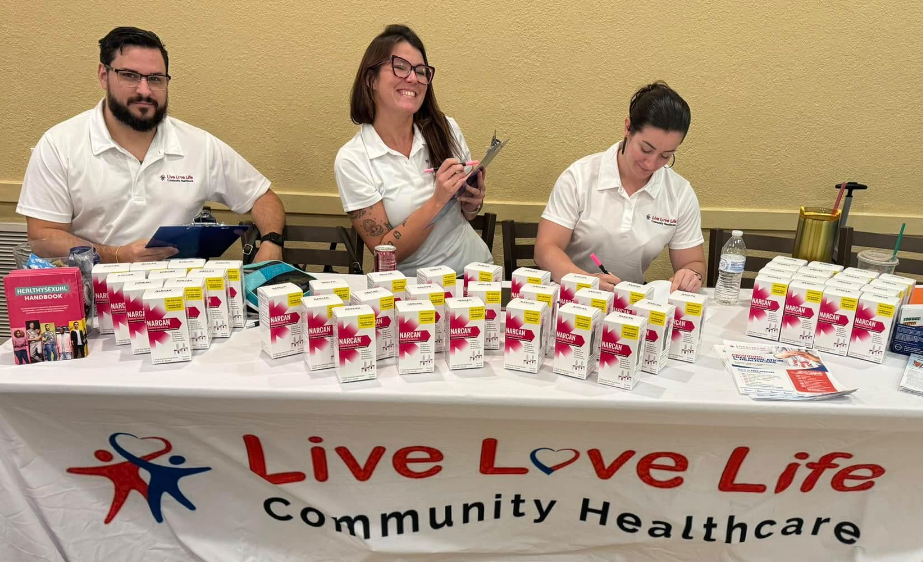 A group of people standing around a table that says live love life community healthcare