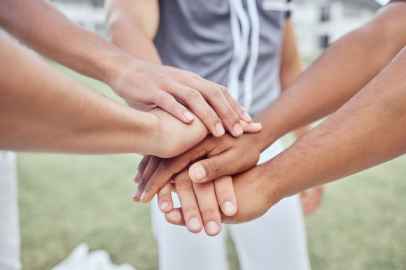 A group of people are putting their hands together on a field.
