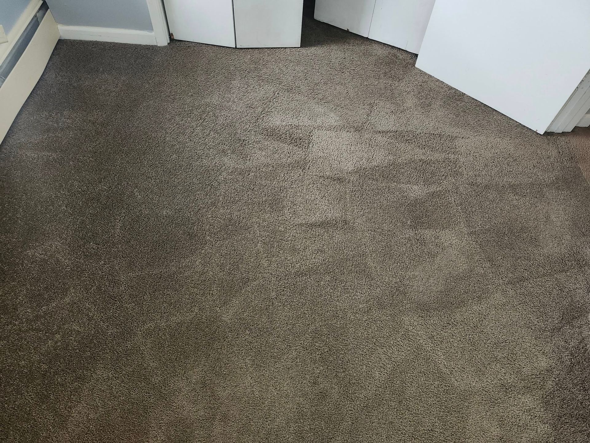 Brown carpet covers the floor, with white furniture on the edge.