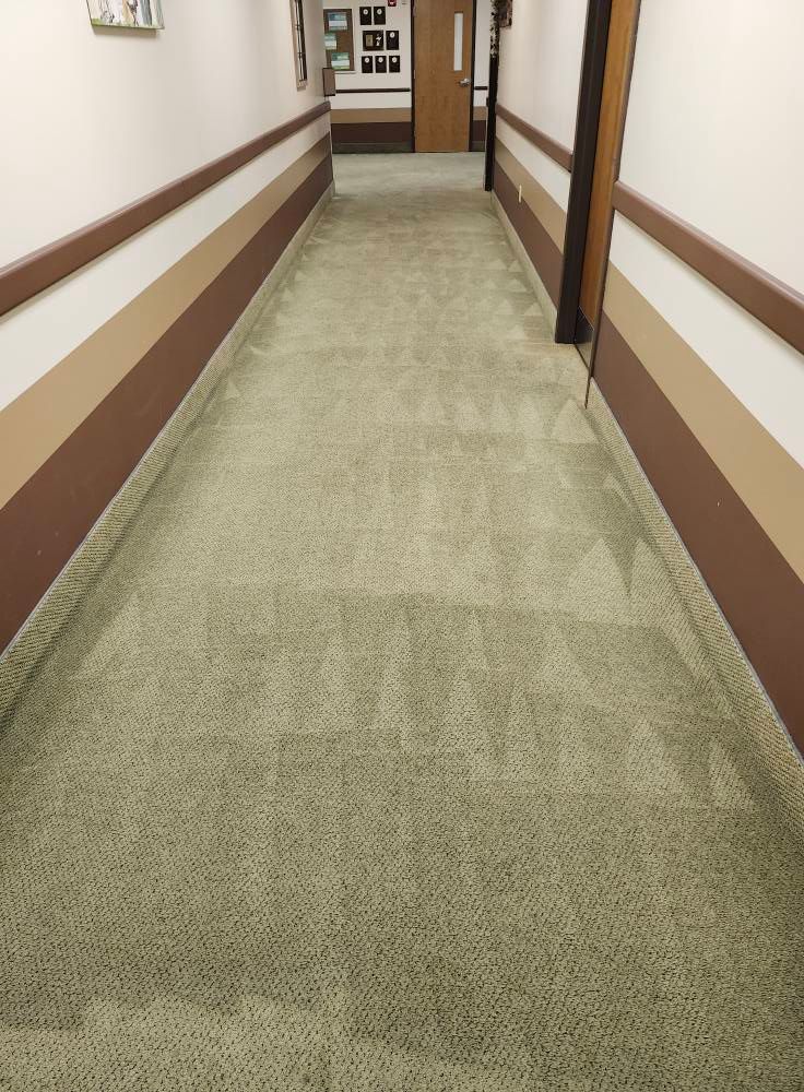 A long, light green carpeted hallway with brown and tan walls.