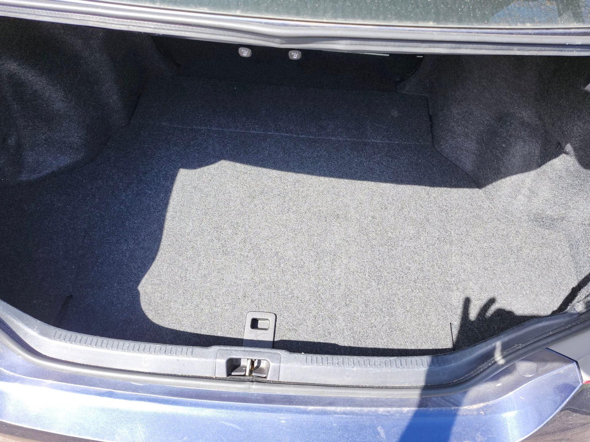 Empty car trunk with gray carpet.