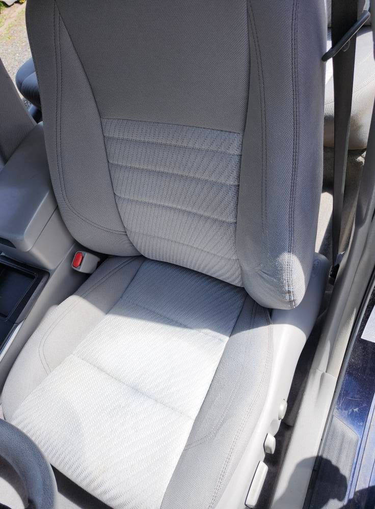 Light gray car seat with patterned back and seatbelt.