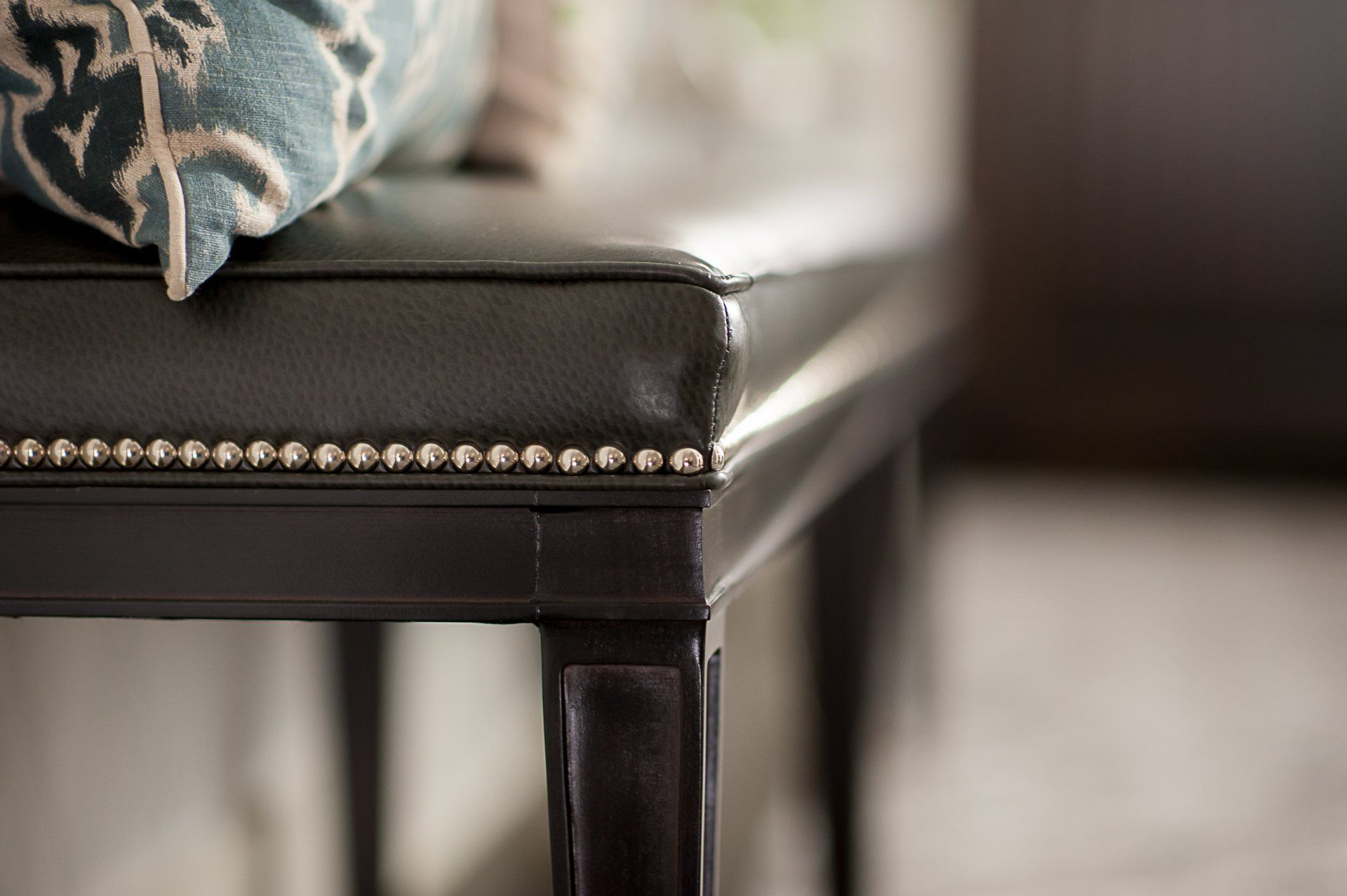 A close up of a leather bench with a pillow on it.