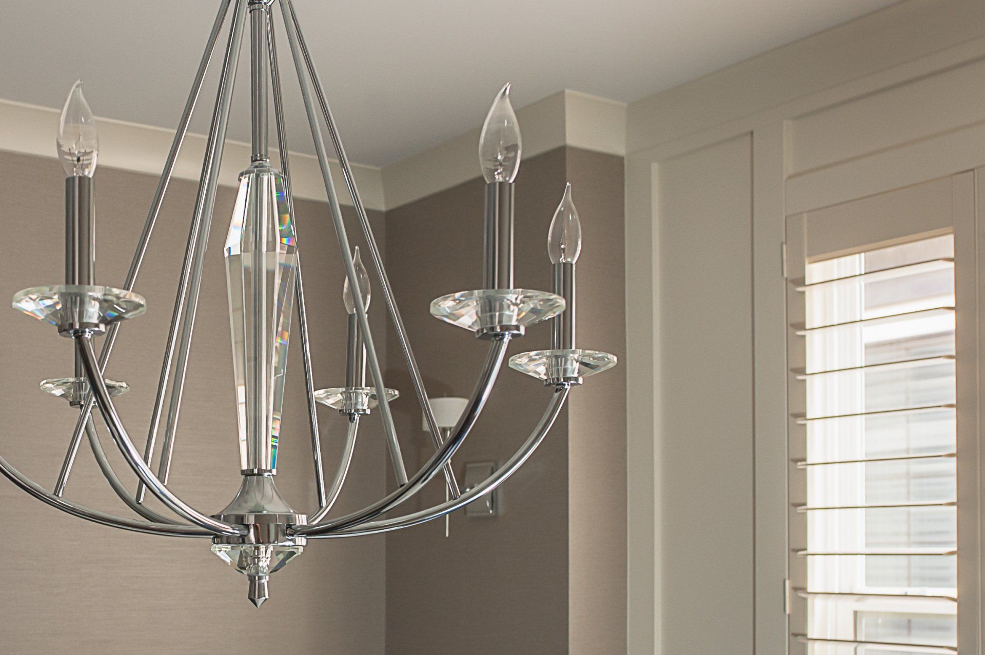 A chandelier is hanging from the ceiling in a room next to a window.