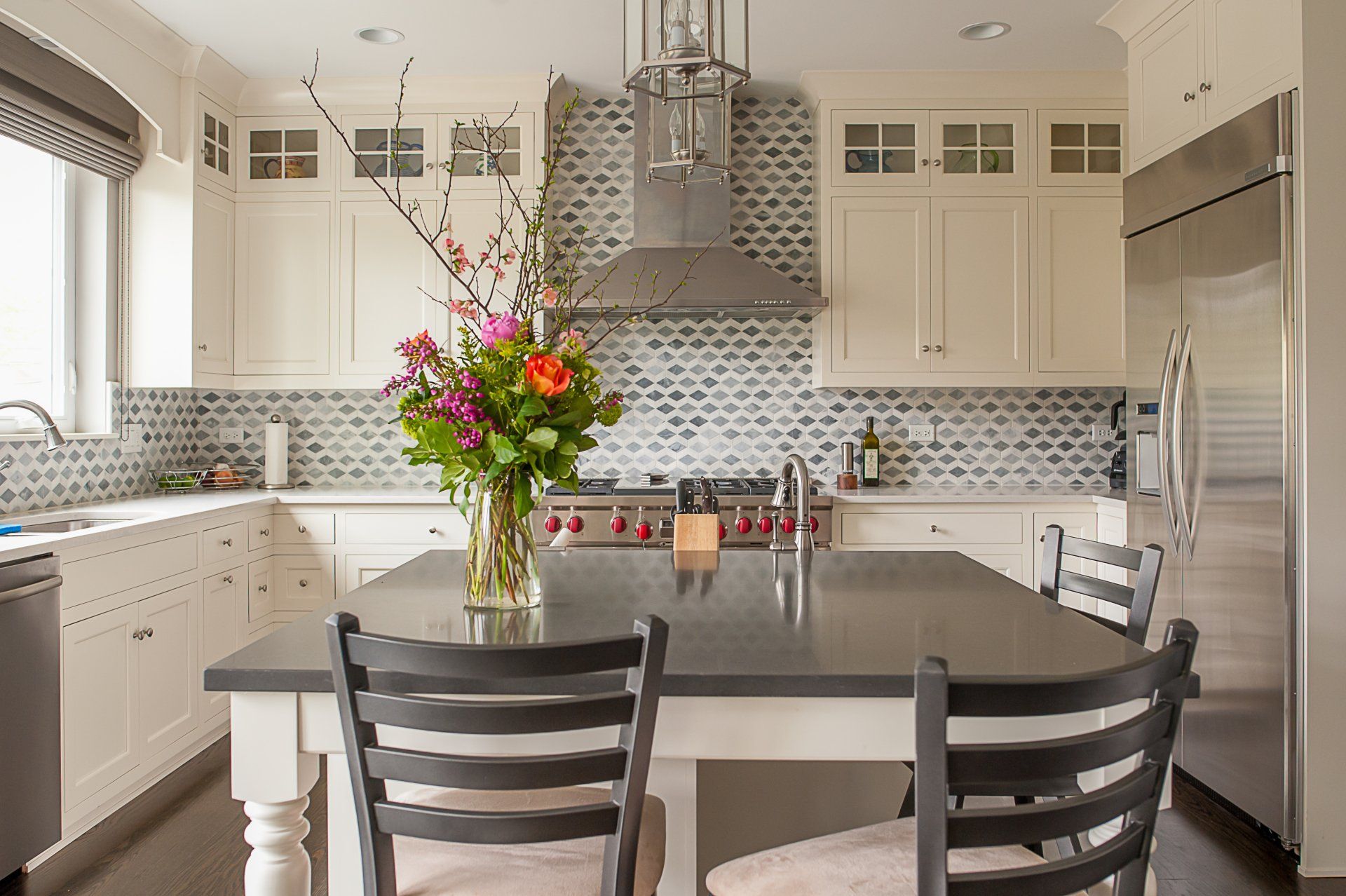 A kitchen with a table and chairs and a vase of flowers on the counter.