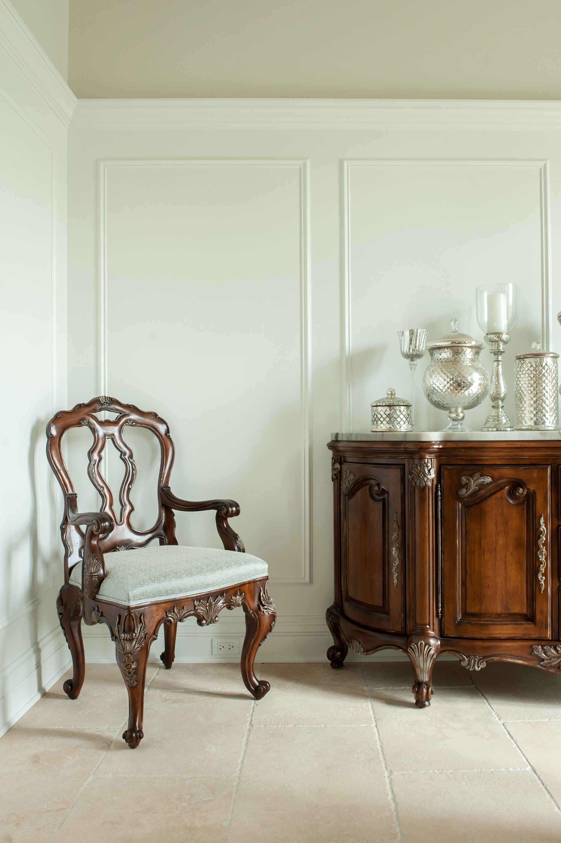 A chair is sitting next to a dresser in a room.