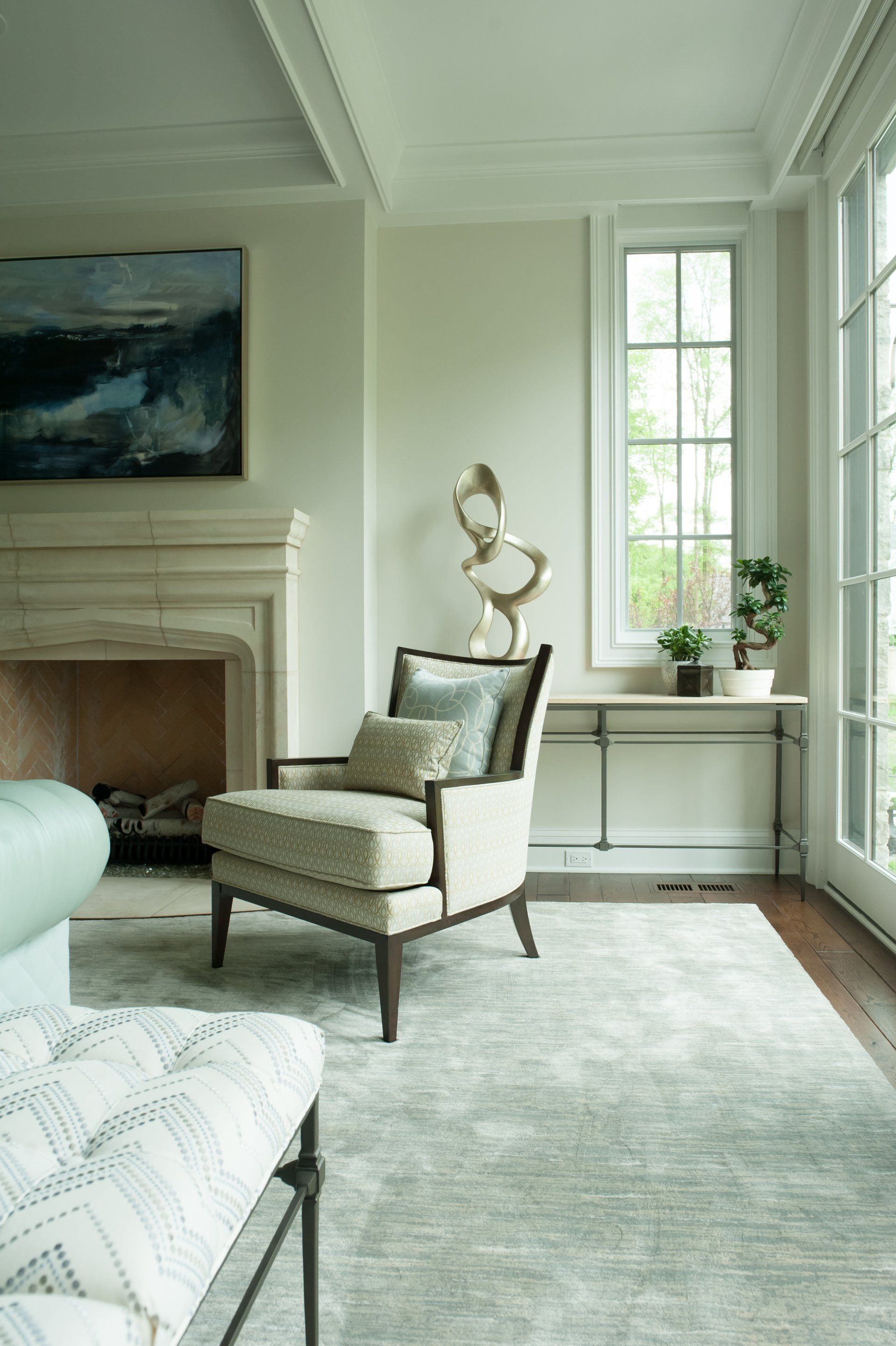 A living room with a fireplace , chair , ottoman and rug.