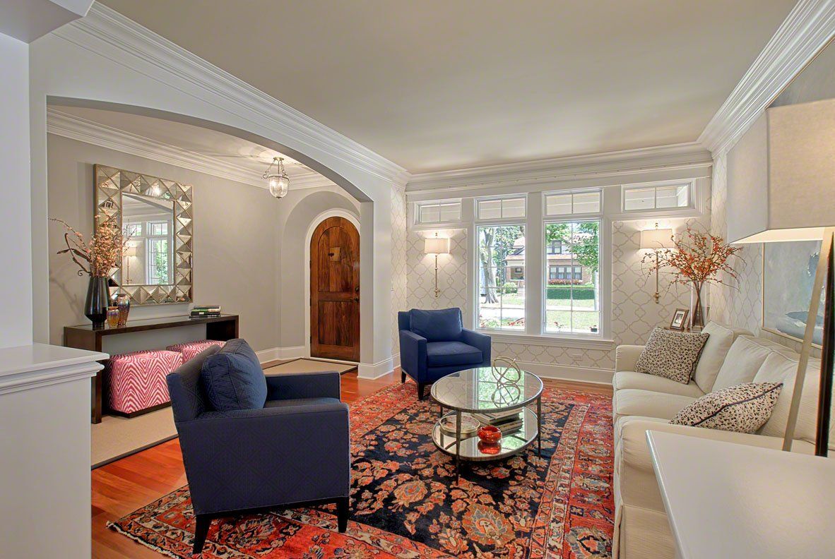 A living room with a couch , two chairs , a coffee table and a rug.