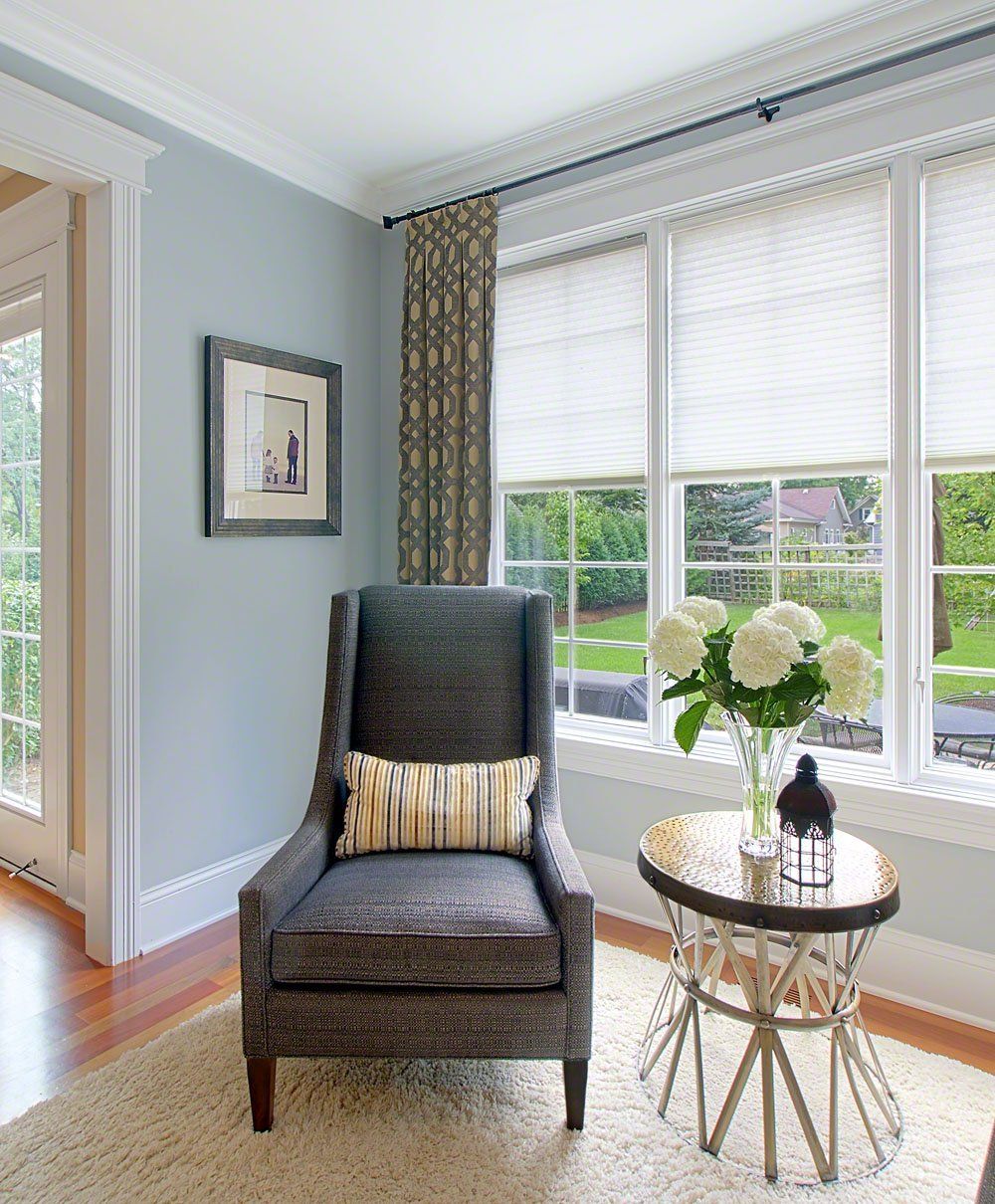 A living room with a chair a table and a vase of flowers