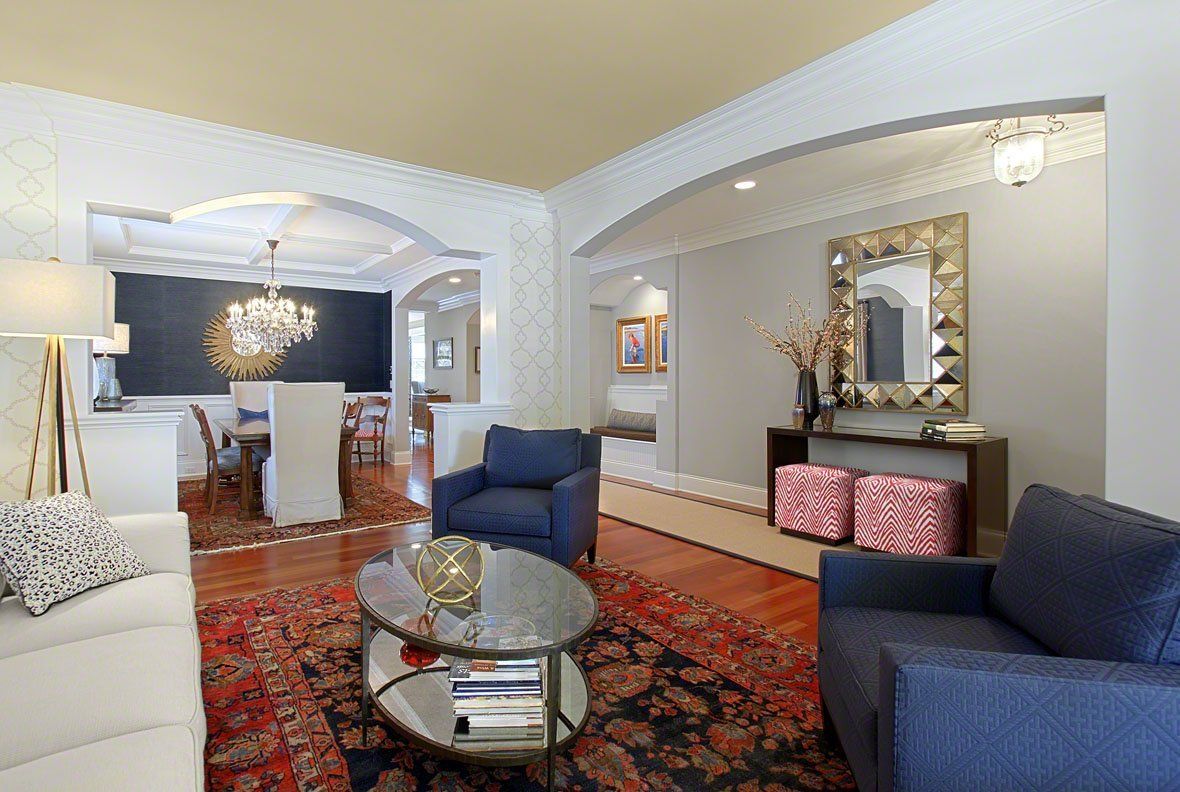 A living room with a couch , chairs , a coffee table and a rug.