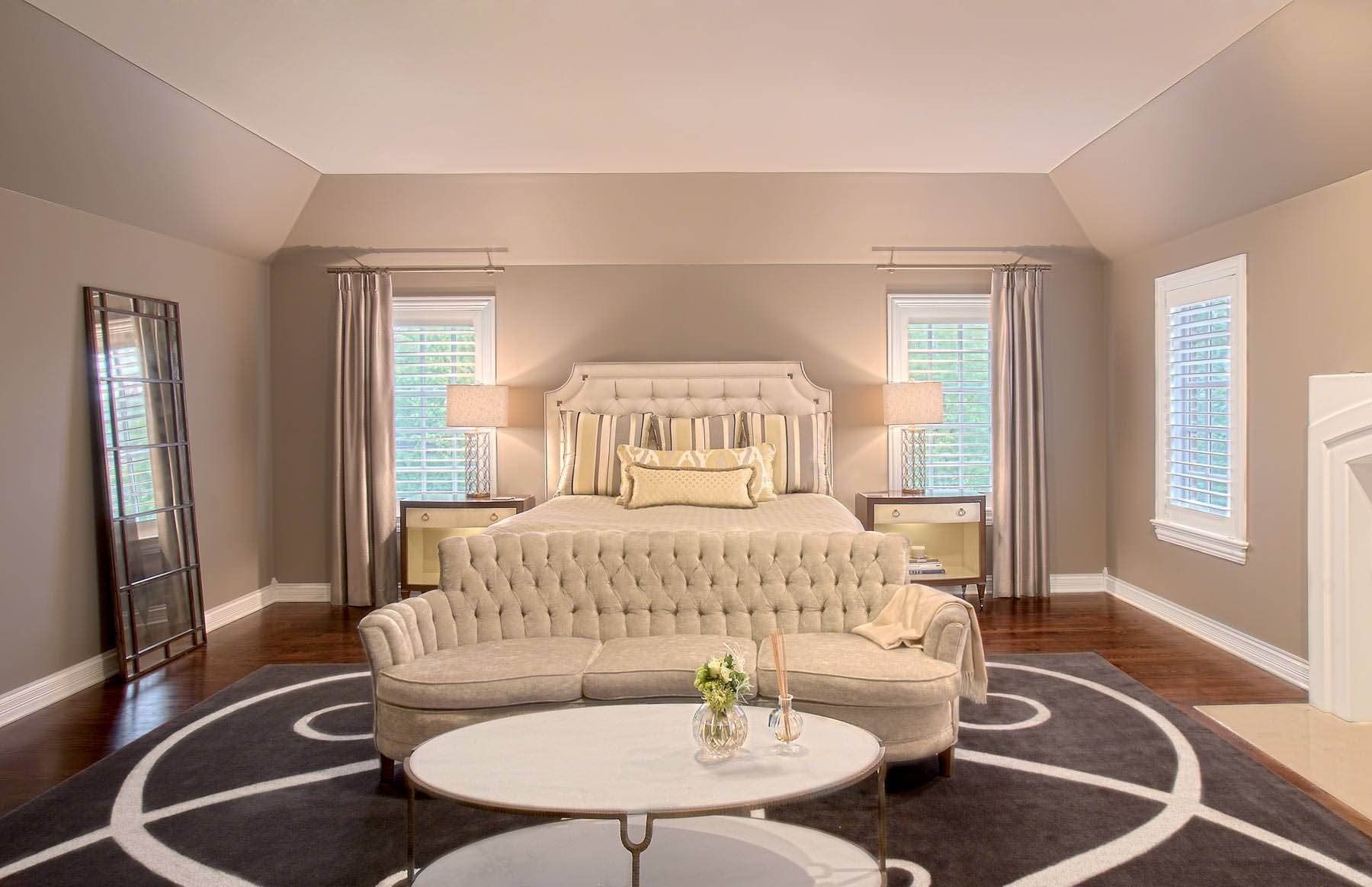 A bedroom with a bed , couch , coffee table and mirror.