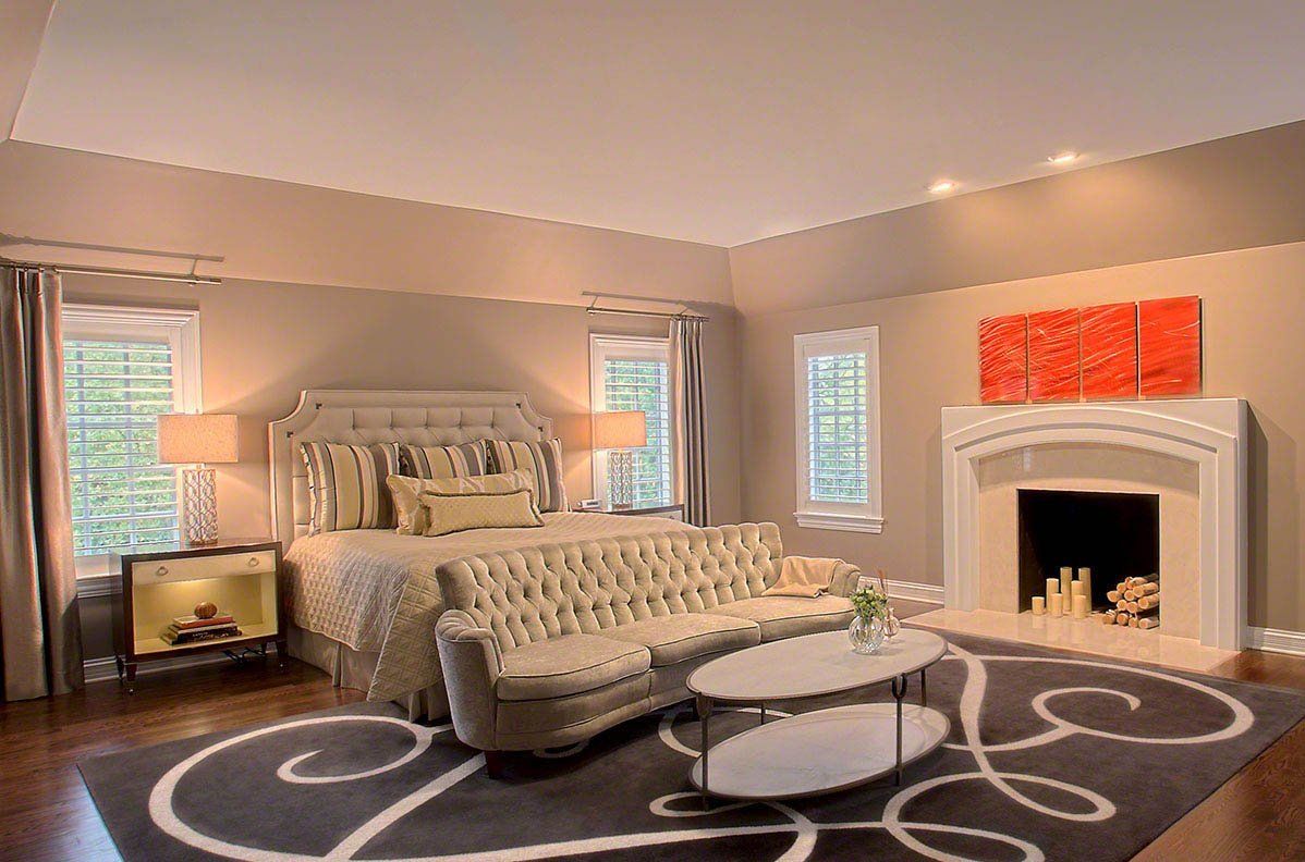 A bedroom with a bed , couch , coffee table and fireplace.