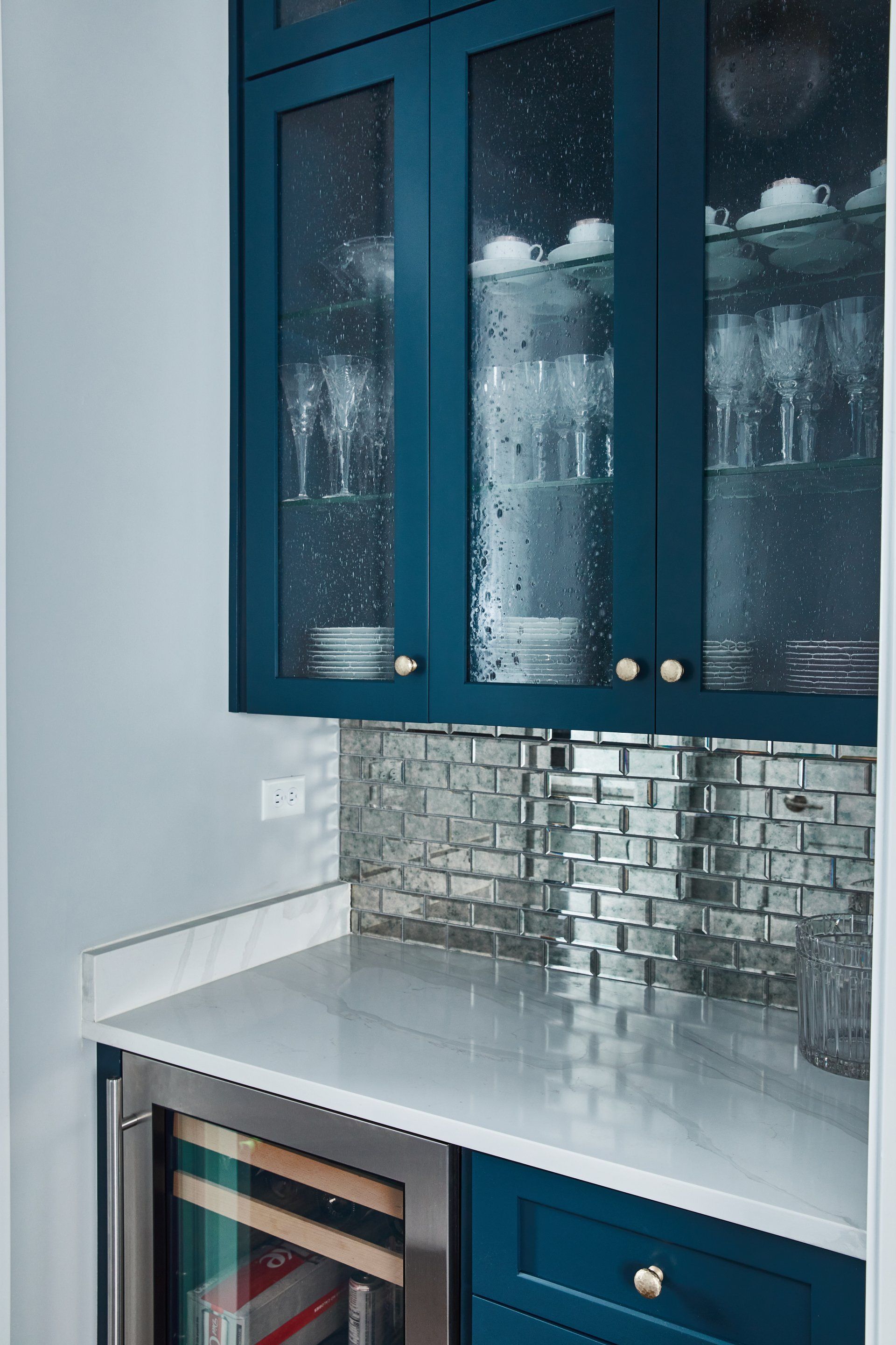 A kitchen with blue cabinets and a wine cooler.