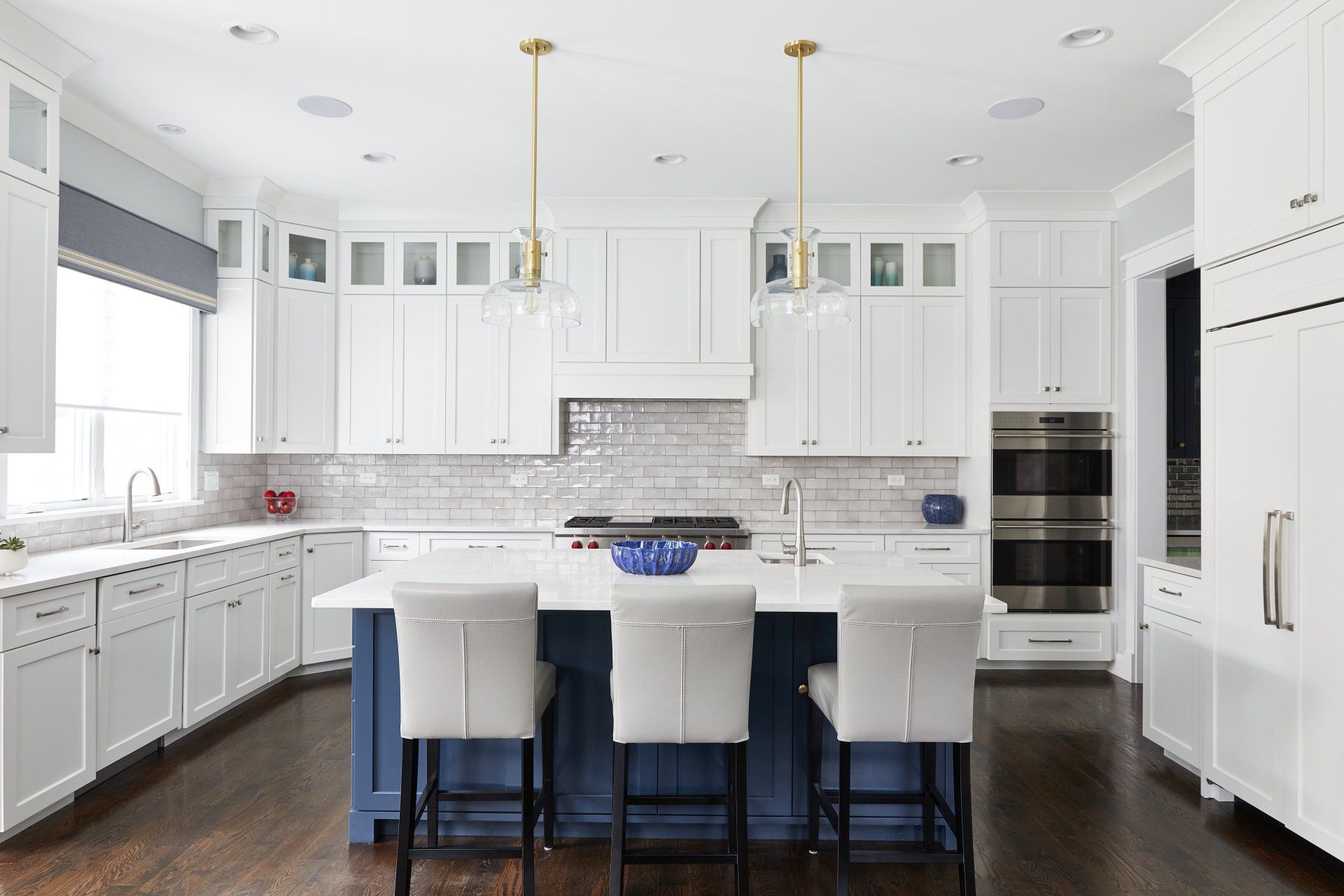 A kitchen with white cabinets and a blue island.