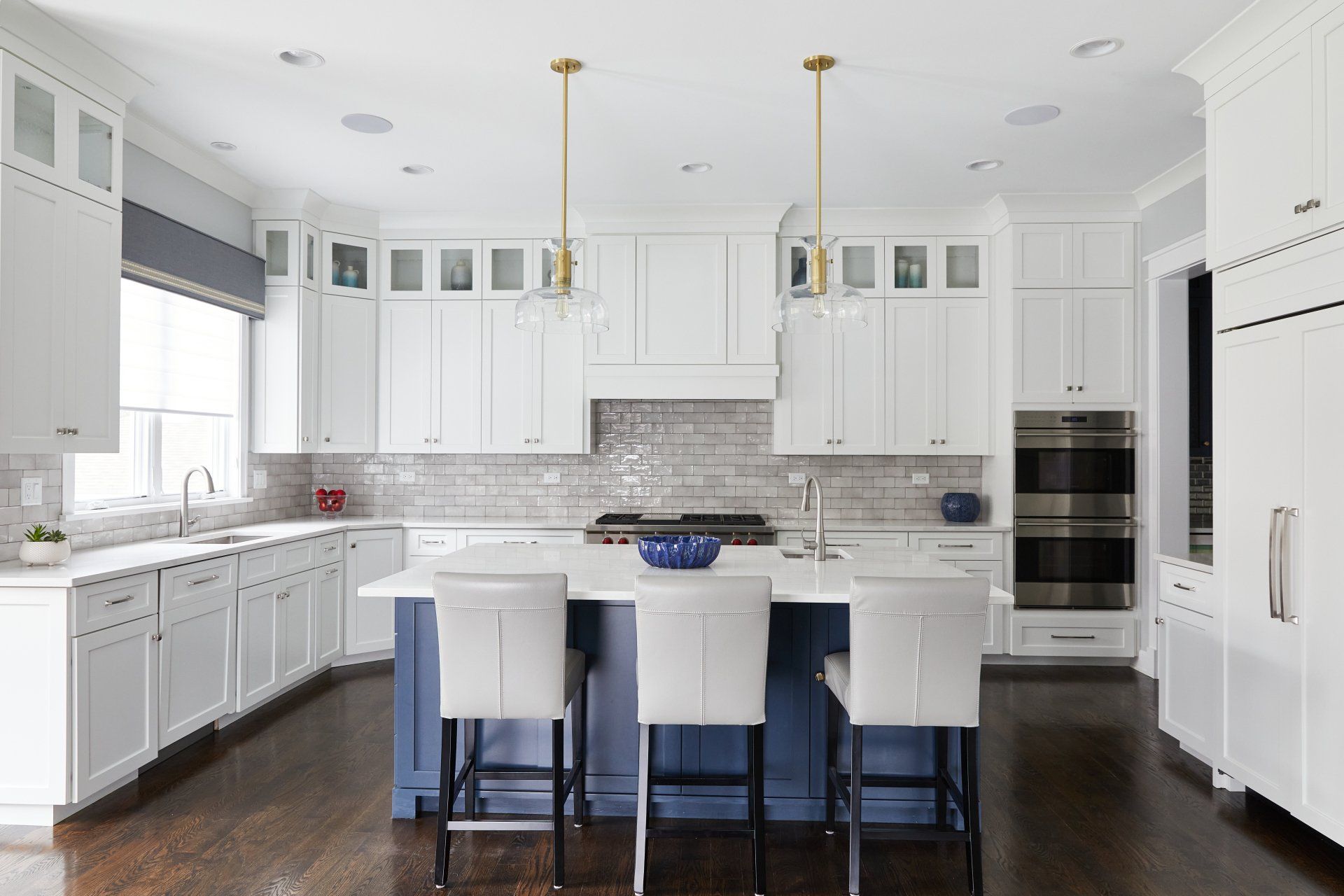 A kitchen with white cabinets and a blue island.