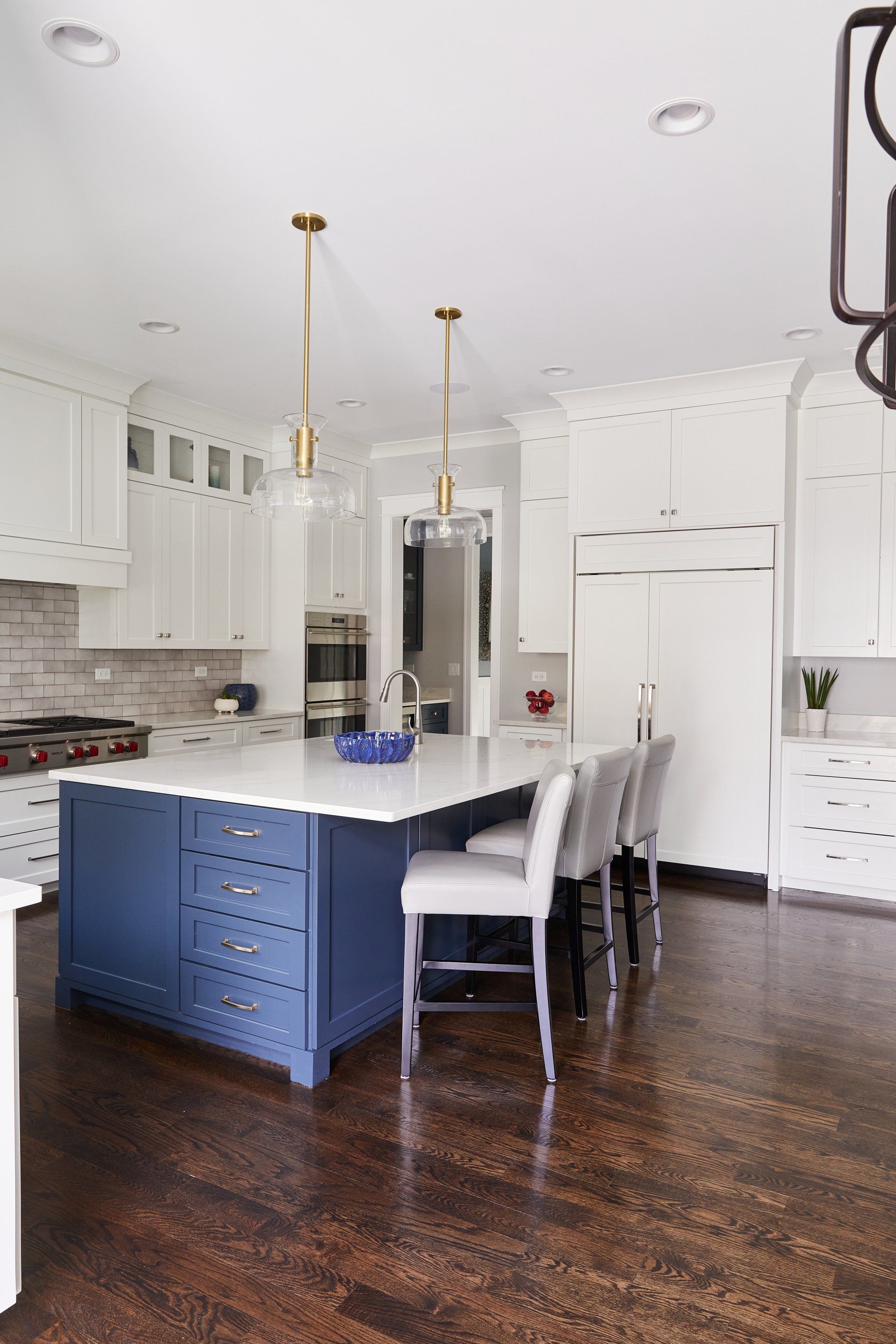 A kitchen with white cabinets and a blue island.