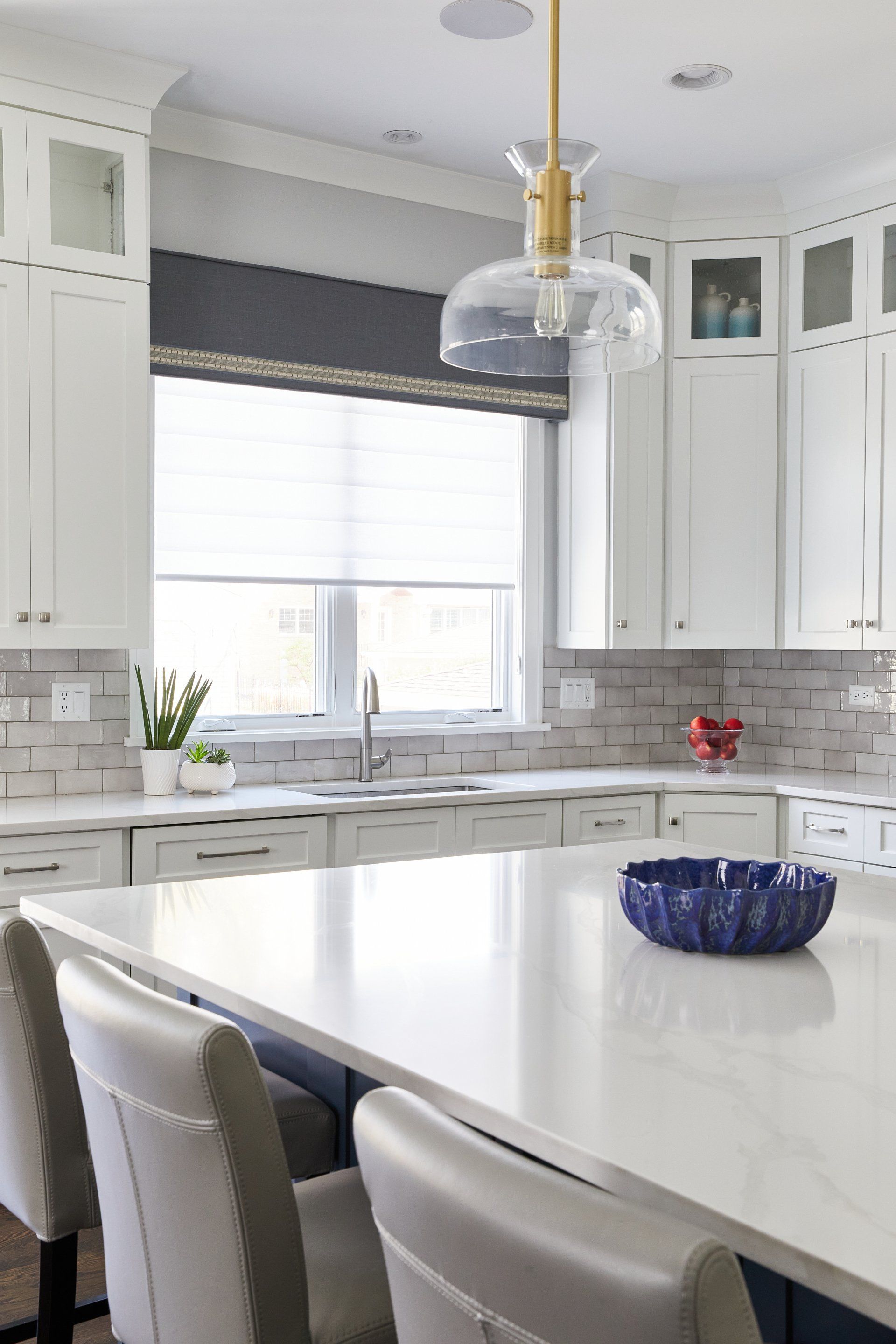 A kitchen with white cabinets and a large island with a bowl on it.