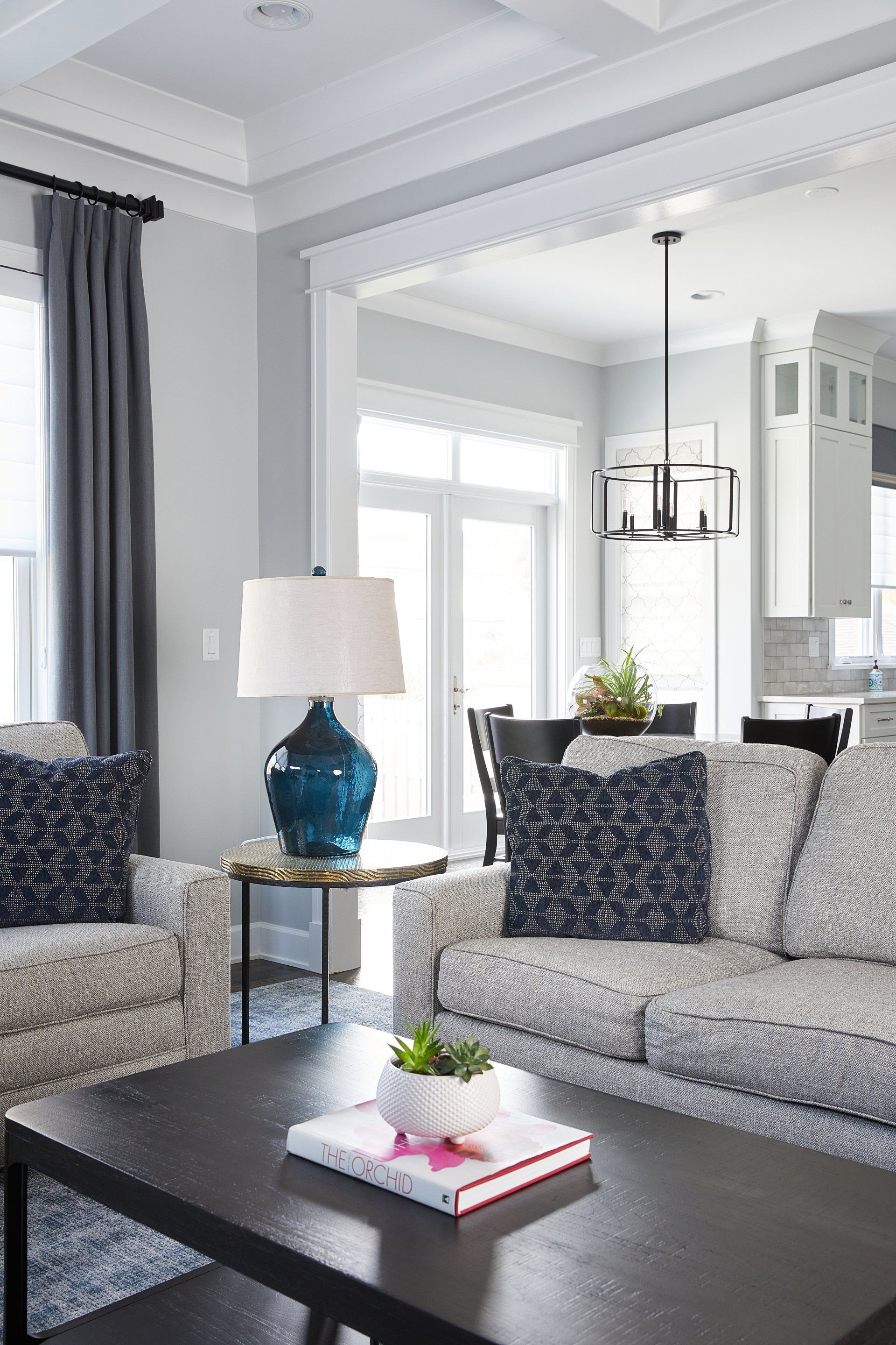 A living room with a couch , chairs , coffee table and lamp.
