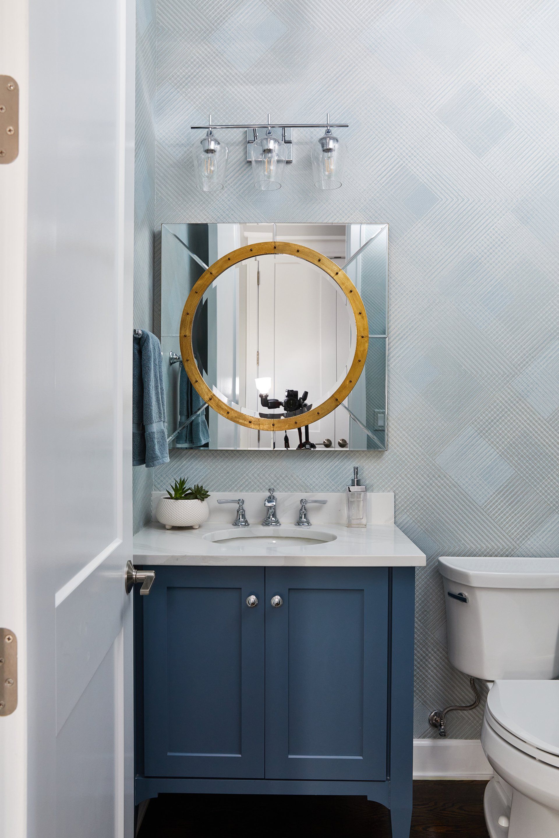 A bathroom with a blue vanity , toilet and mirror.