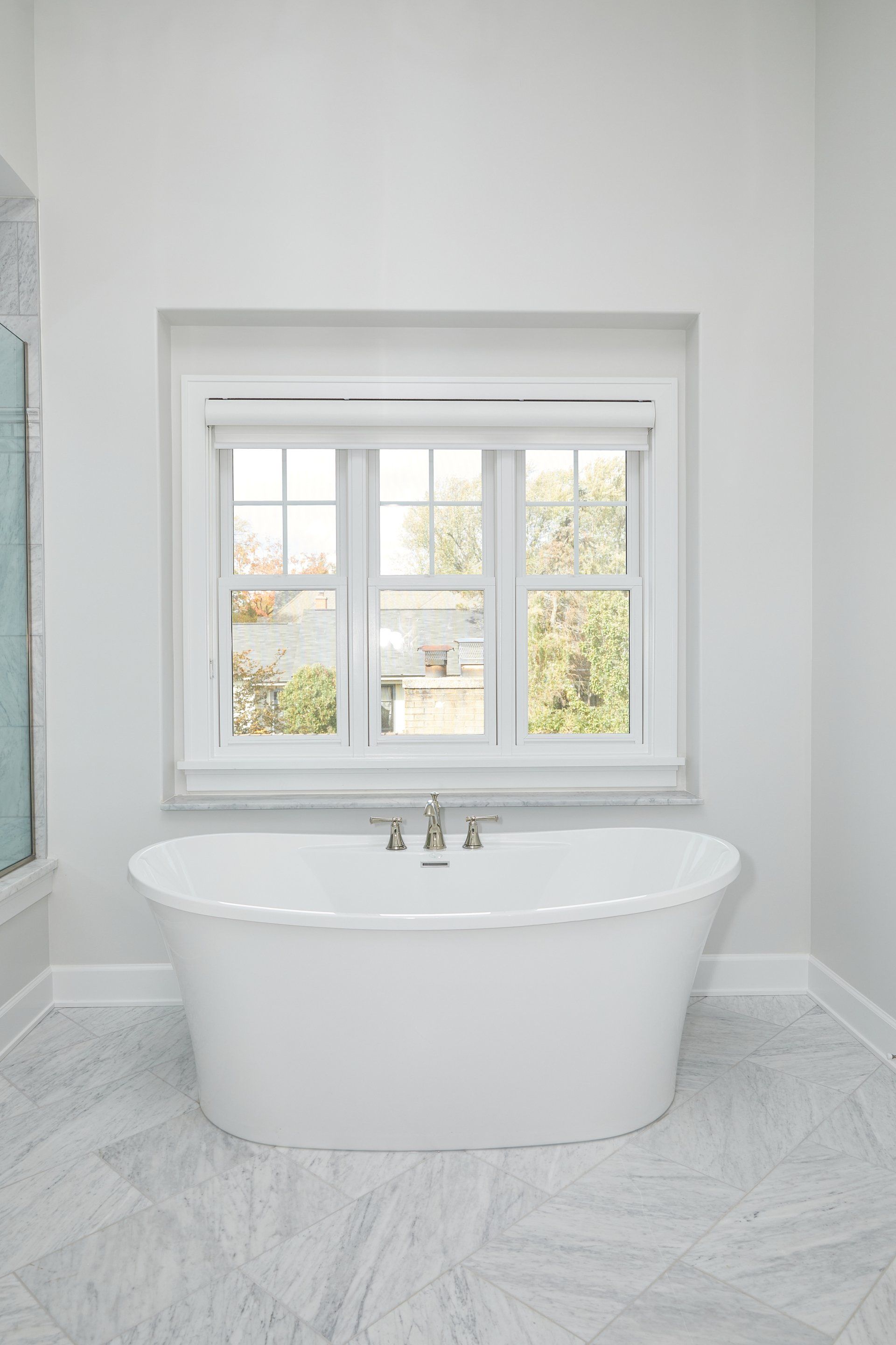 A white bathtub is sitting in a bathroom next to a window.