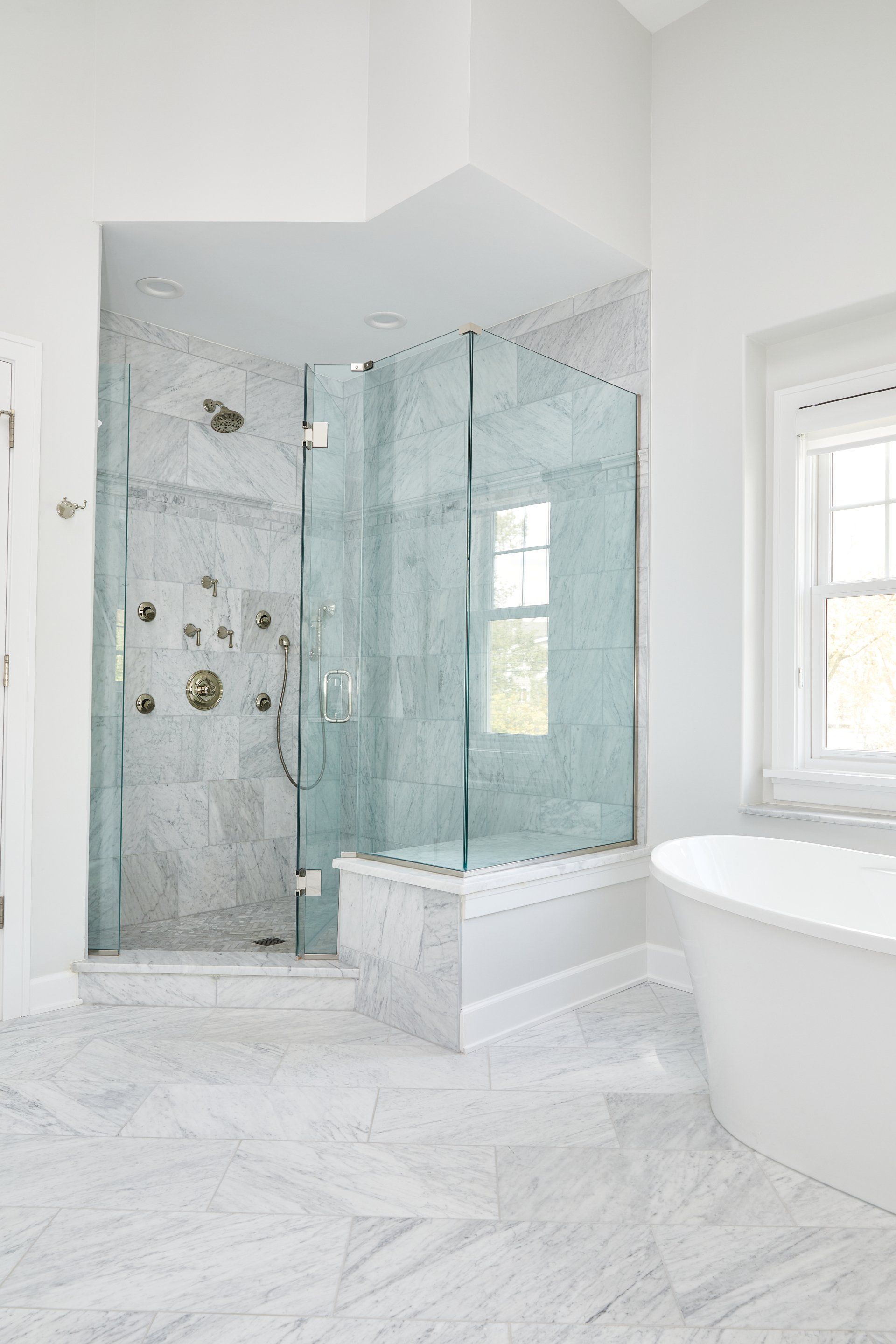 A bathroom with a walk in shower , tub and window.