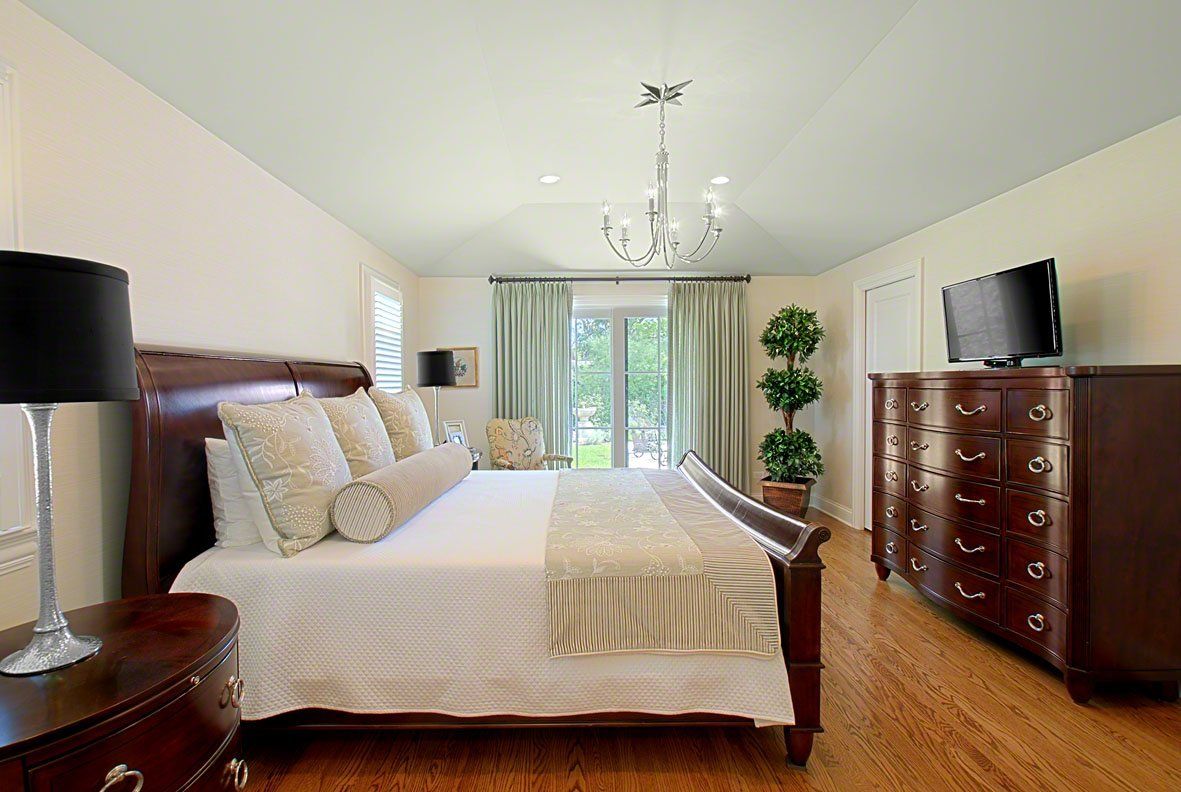 A bedroom with a large bed , dresser , nightstand and television.