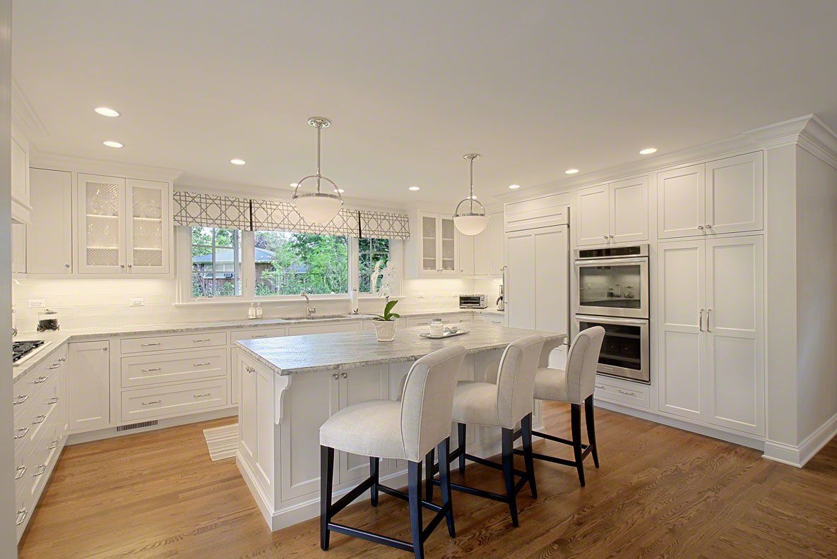 A kitchen with white cabinets and hardwood floors and a large island.