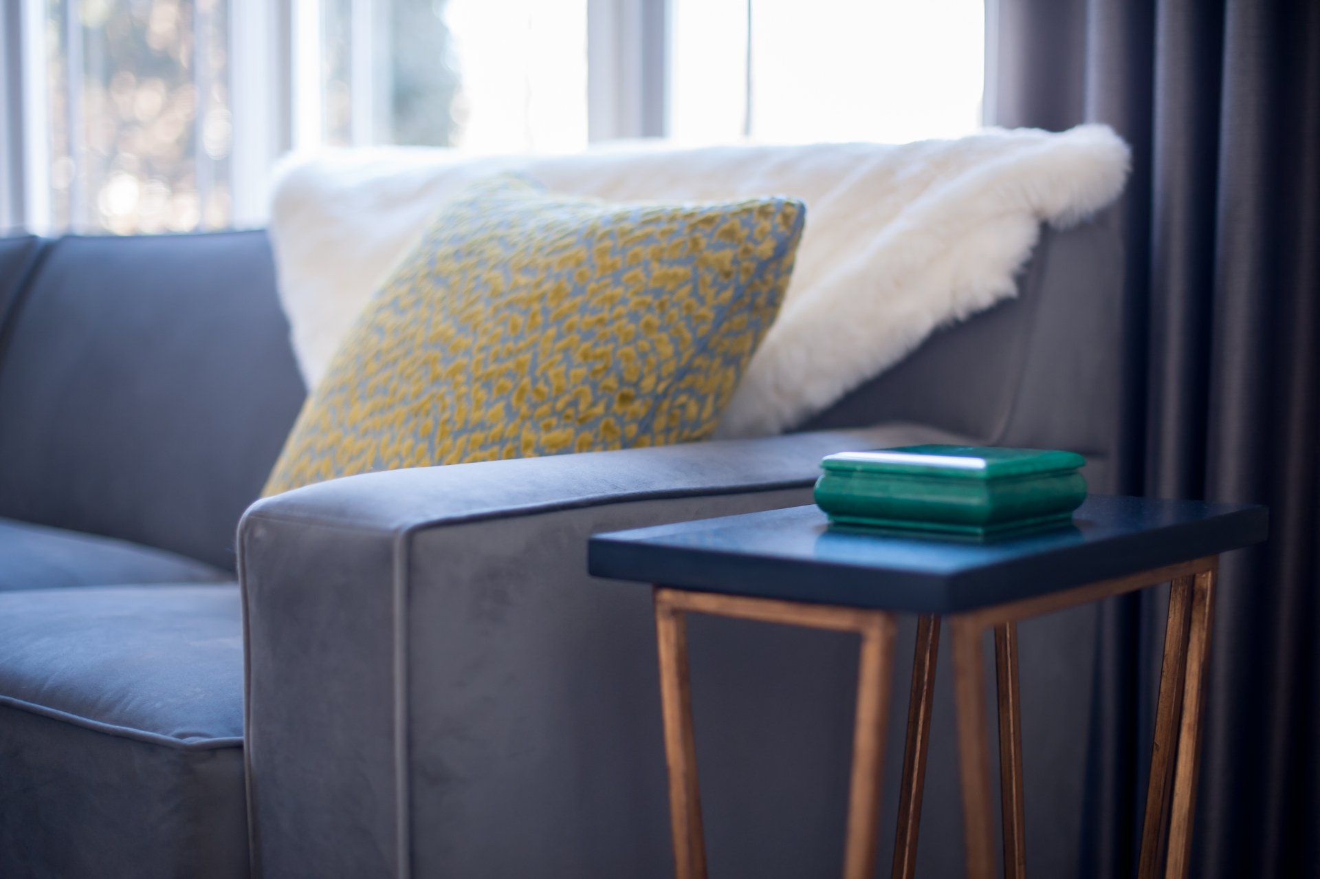 A living room with a couch , a table , and a window.