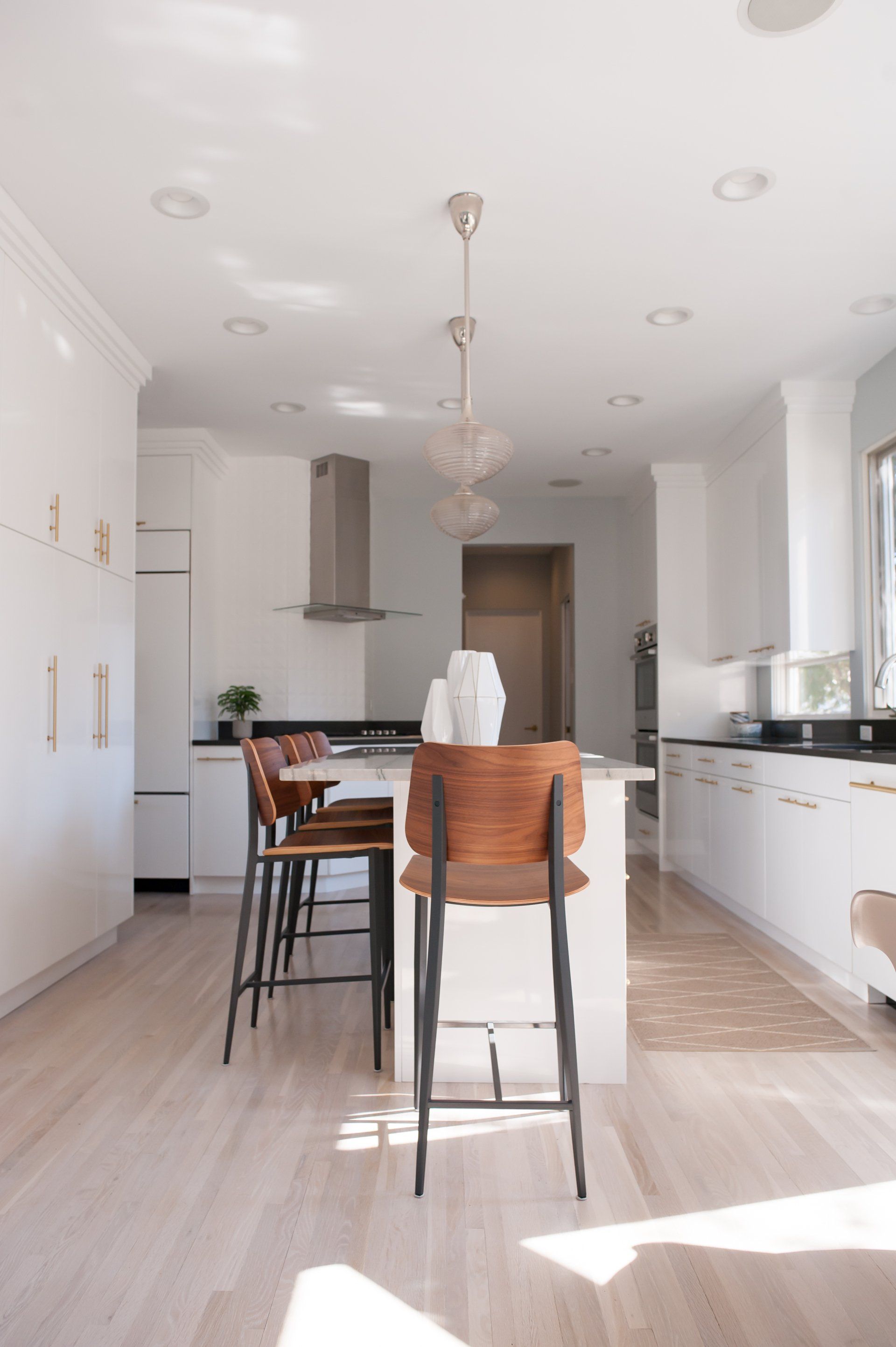 A kitchen with white cabinets and wooden stools