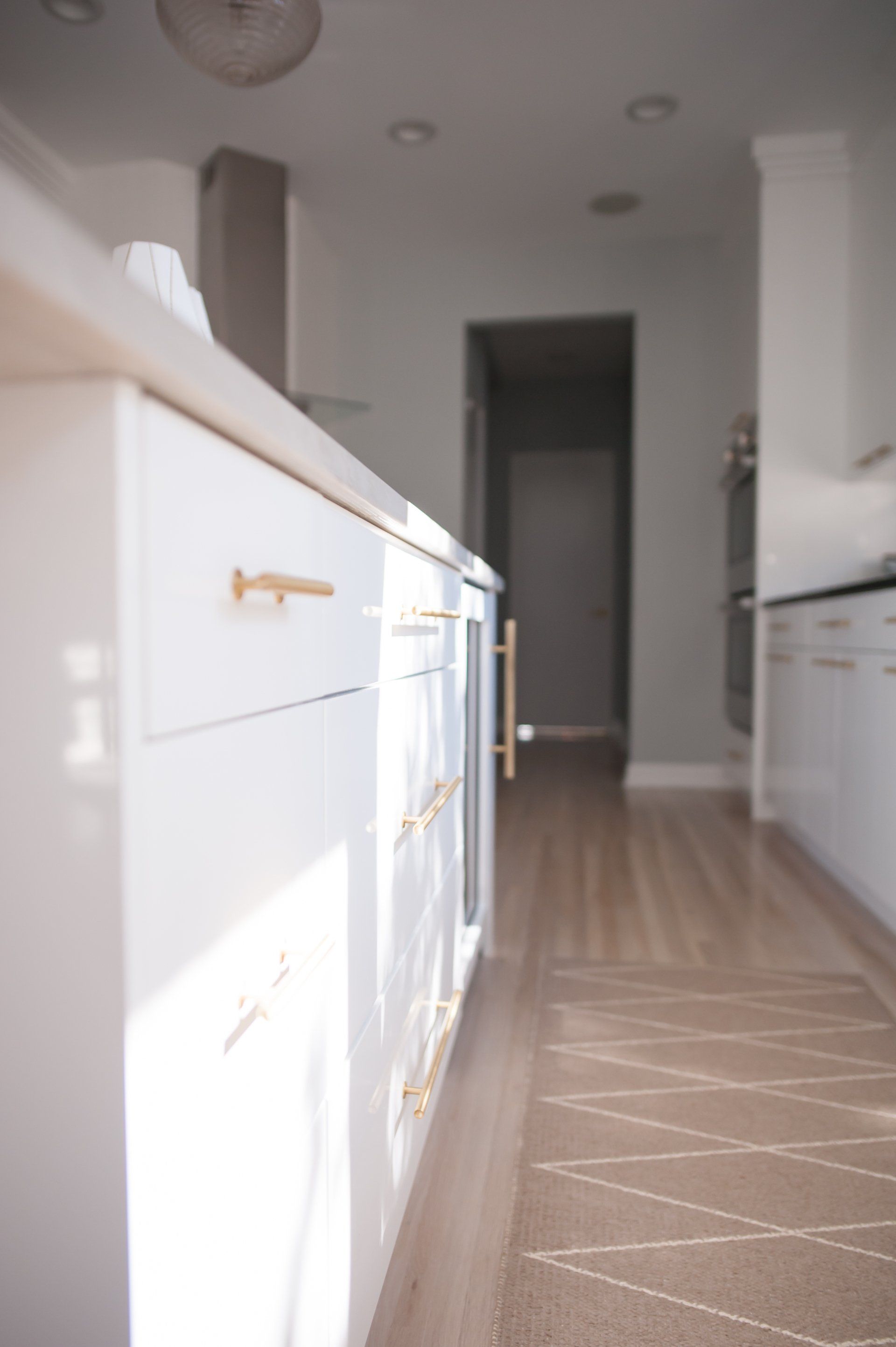 A kitchen with white cabinets and gold handles
