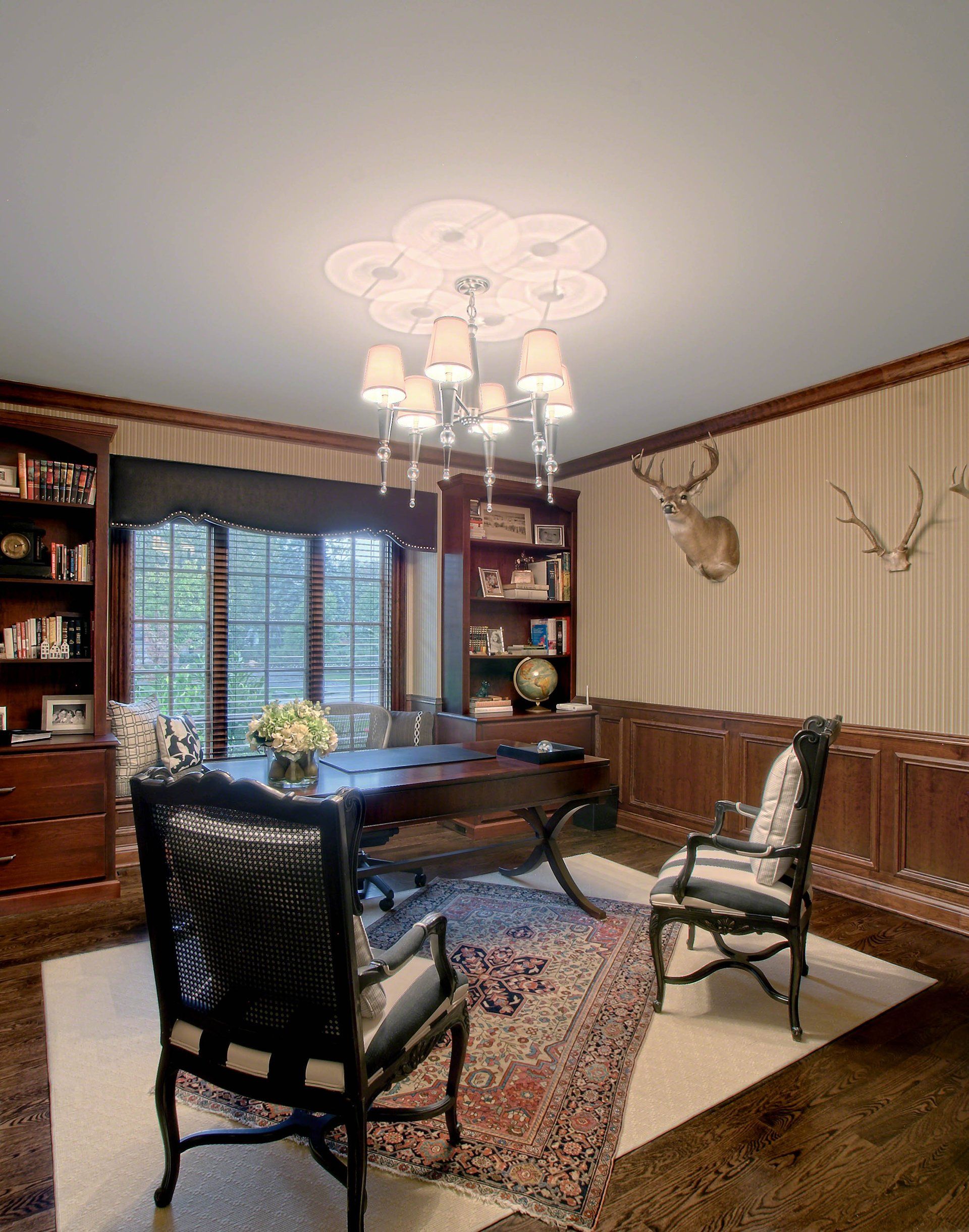 A room with a desk and chairs and a deer head on the wall