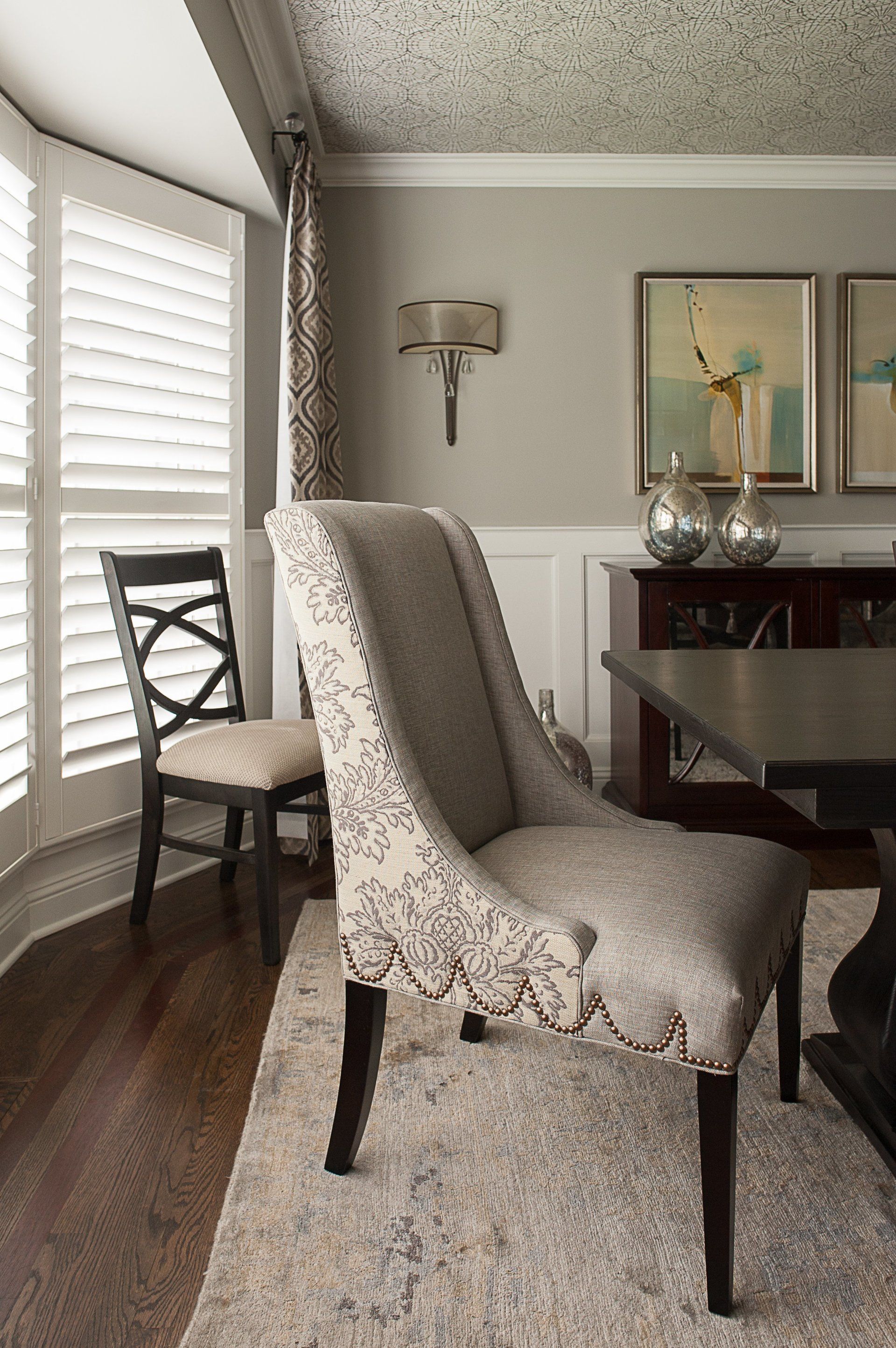 A dining room with a table and chairs and shutters on the windows.