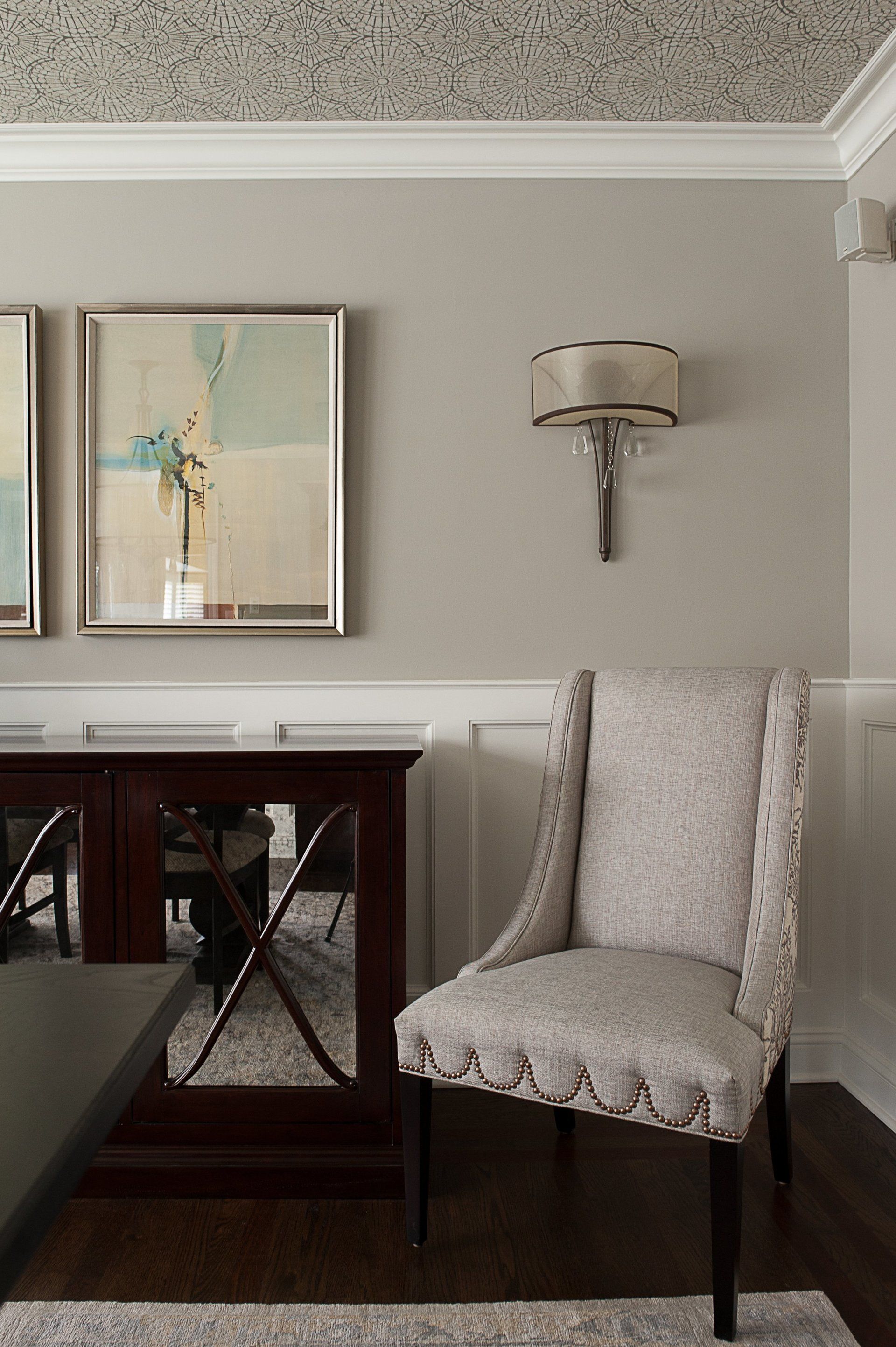 A living room with a chair , a table , and a painting on the wall.