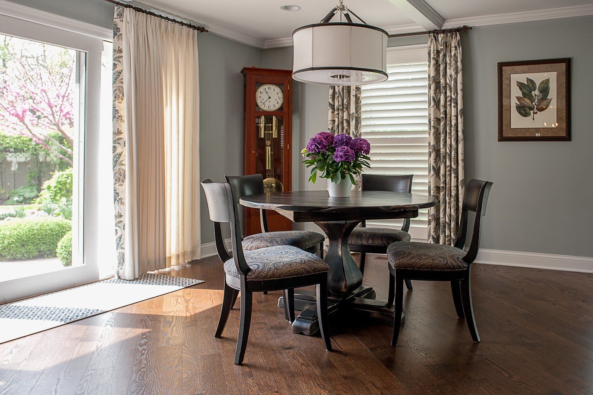 A dining room with a table and chairs and a grandfather clock.